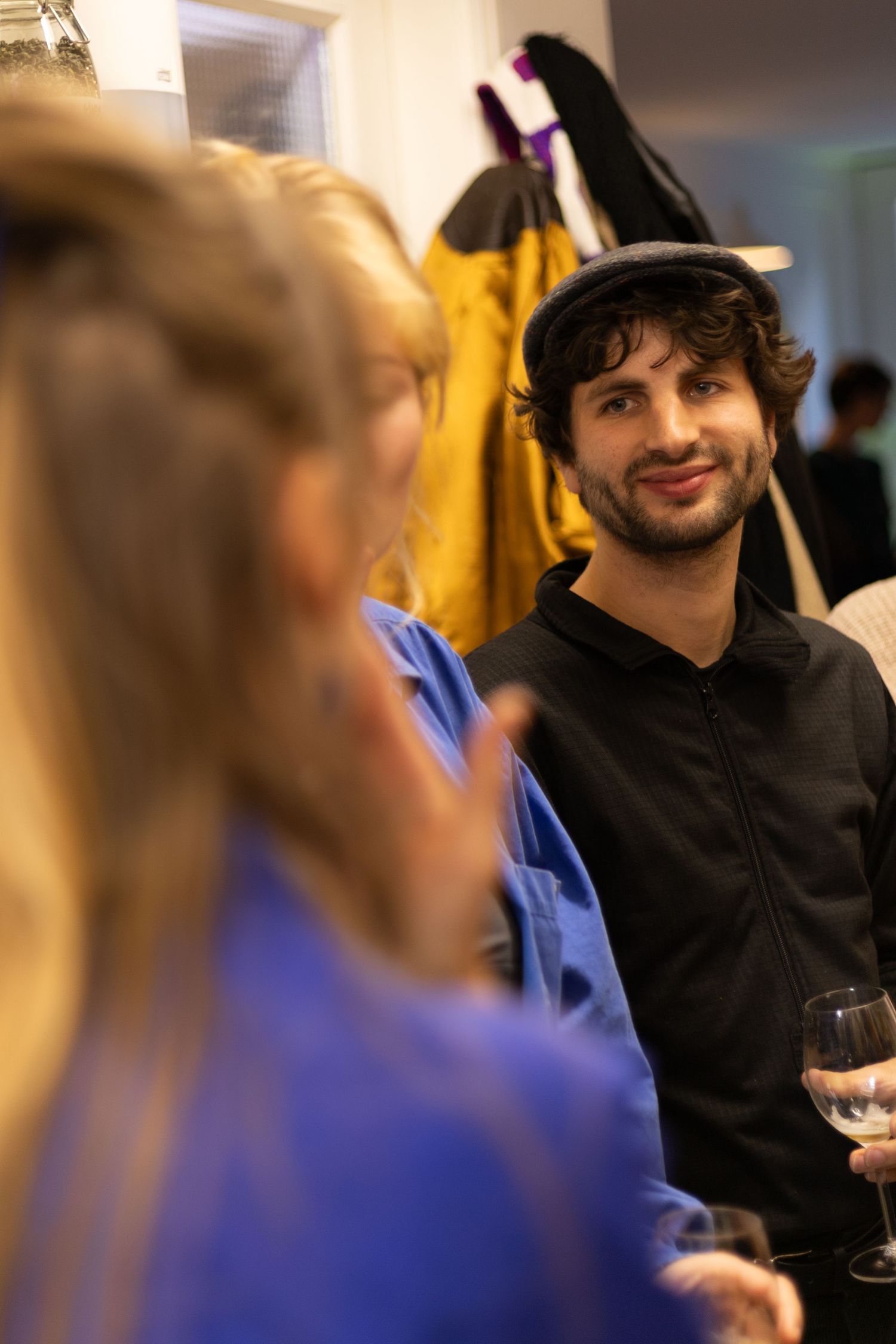 People socializing and smiling at an indoor gathering with festive lighting and decor.