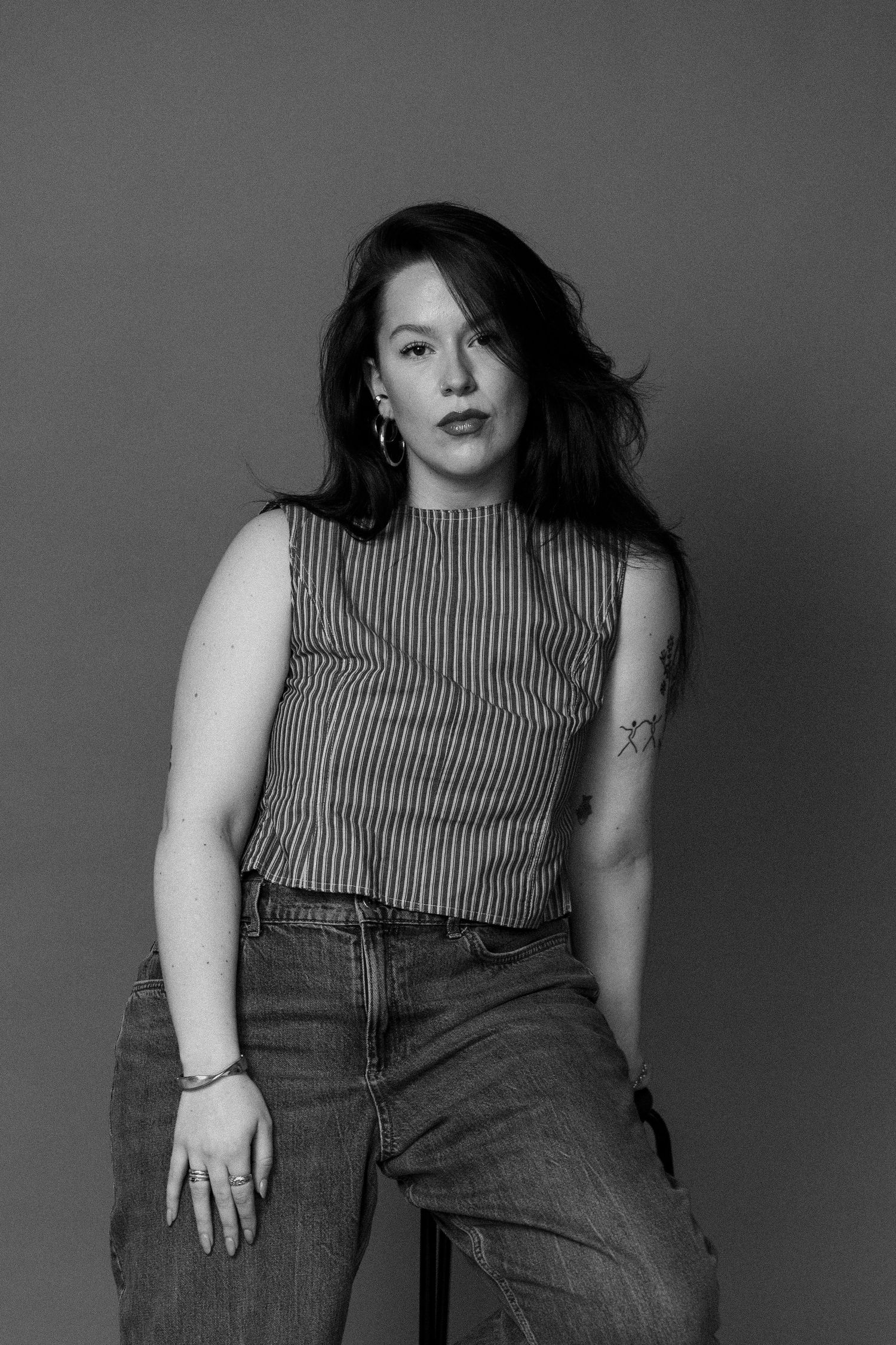 Black and white fashion photo series showing a person in a striped sleeveless top and denim jeans posing against a plain backdrop.