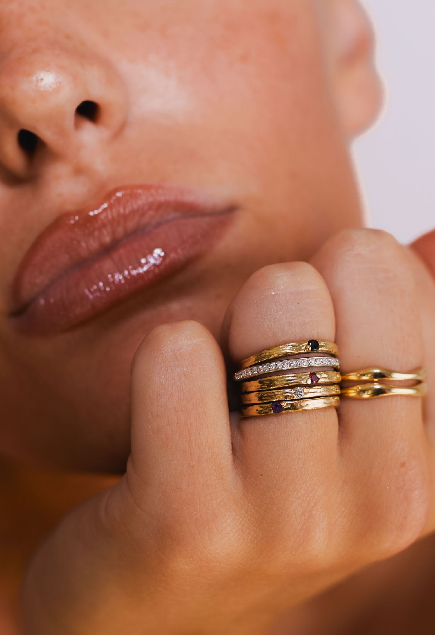 Close-up view of delicate gold rings stacked together against natural skin tone.