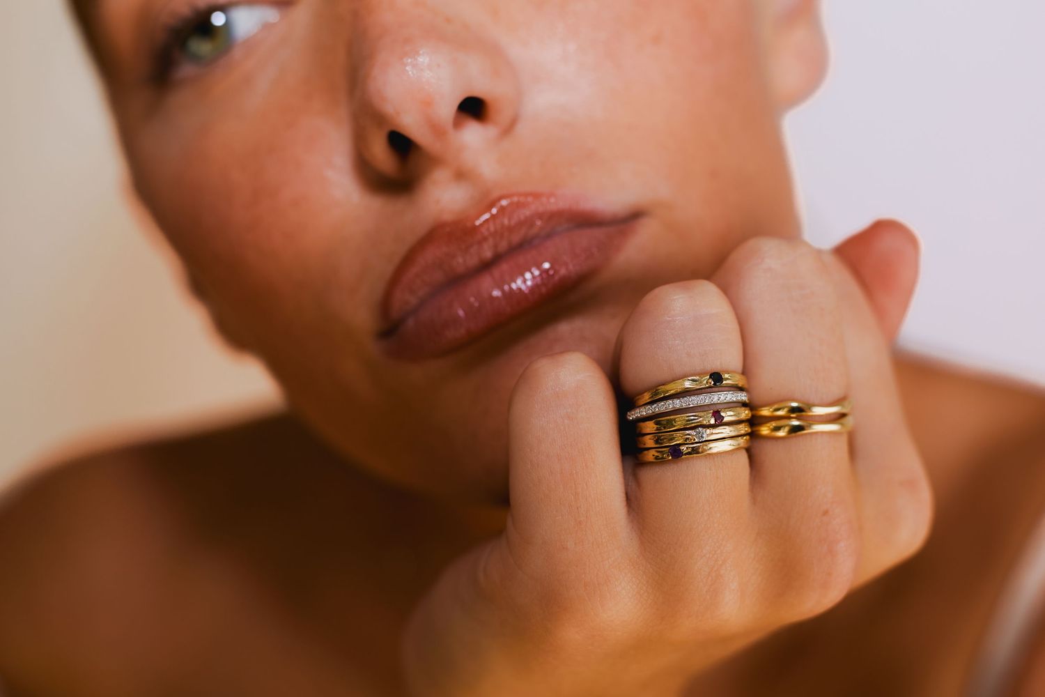 Macro beauty shot focusing on jewelry rings and natural makeup details.