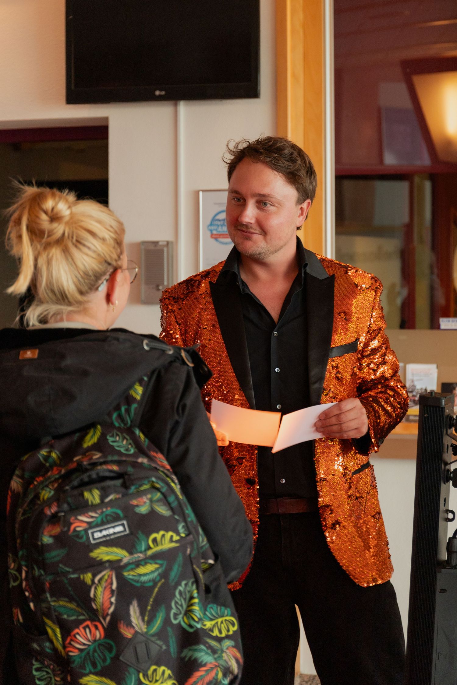 A sequence of five photos showing a person in a sparkly orange jacket interacting with someone wearing a floral print jacket.