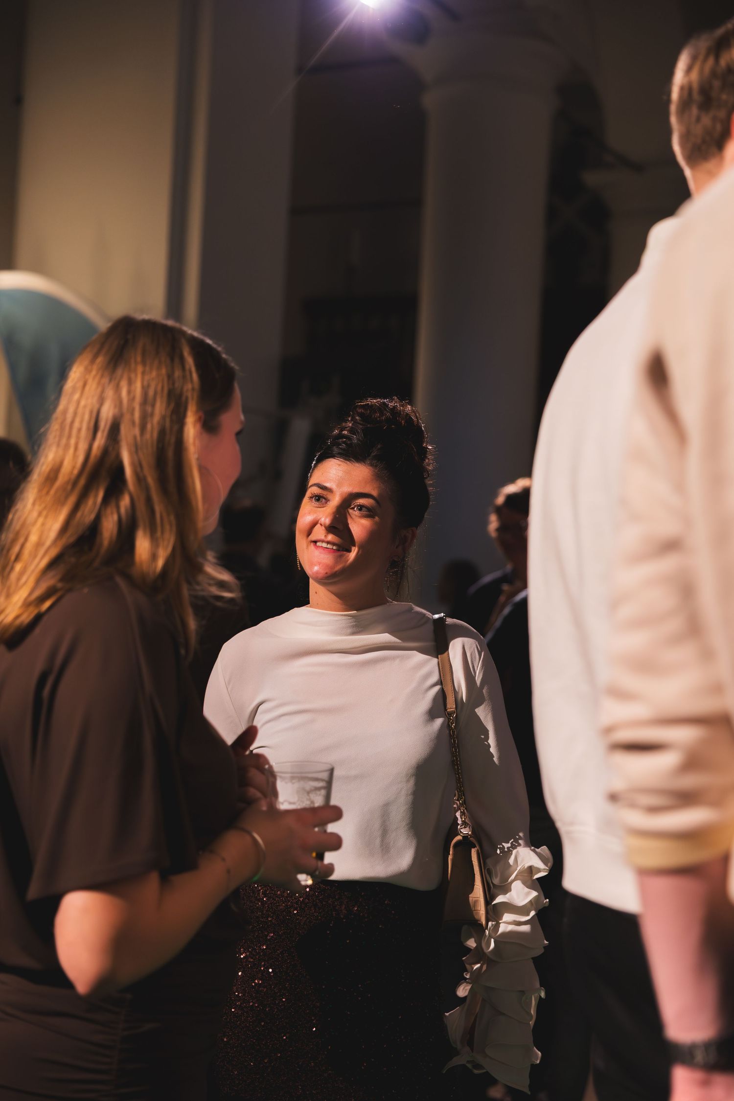 People engaged in casual conversation at an evening social gathering with warm lighting.