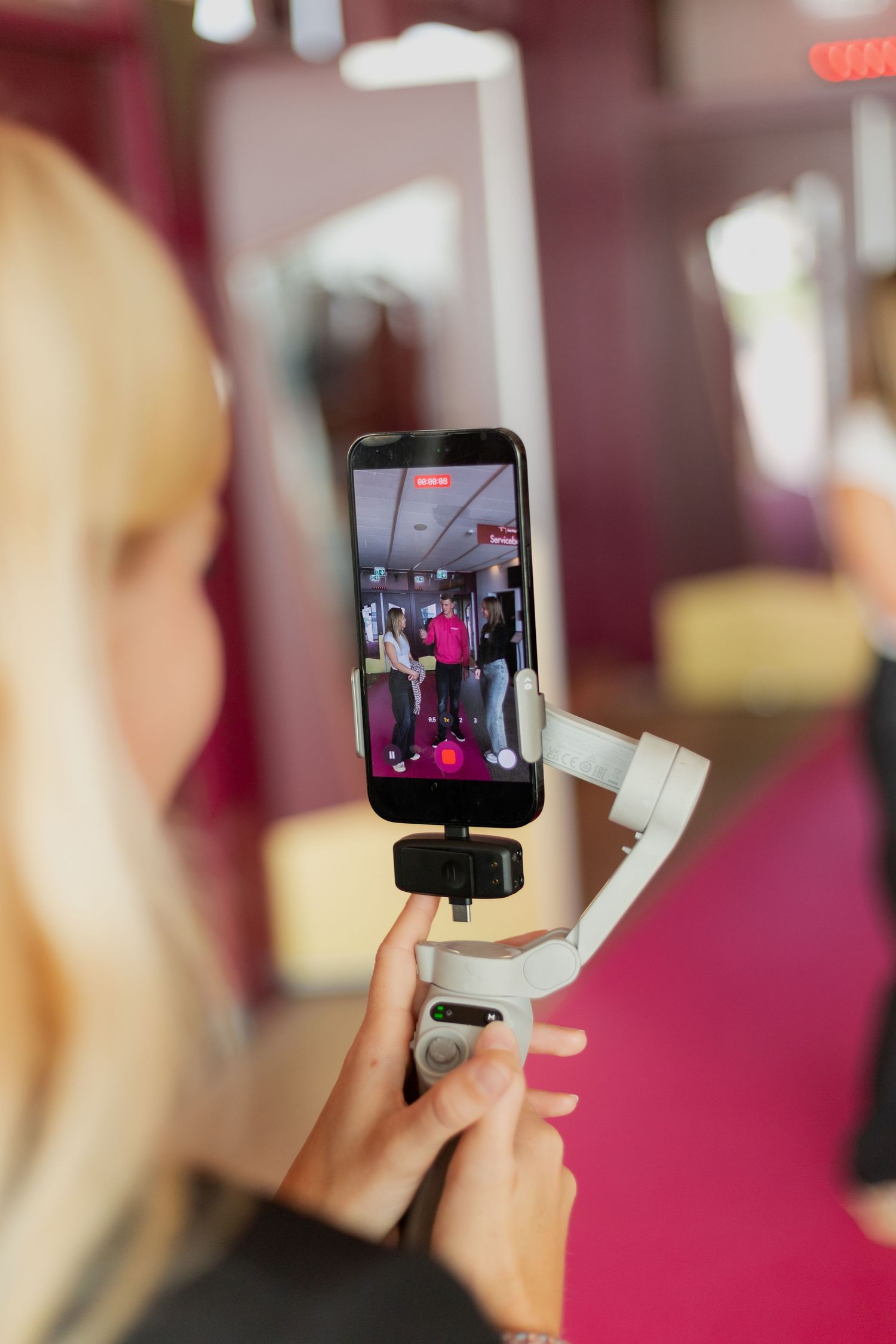 A sequence of smartphone screens showing a person recording video content in a pink-tinted room.