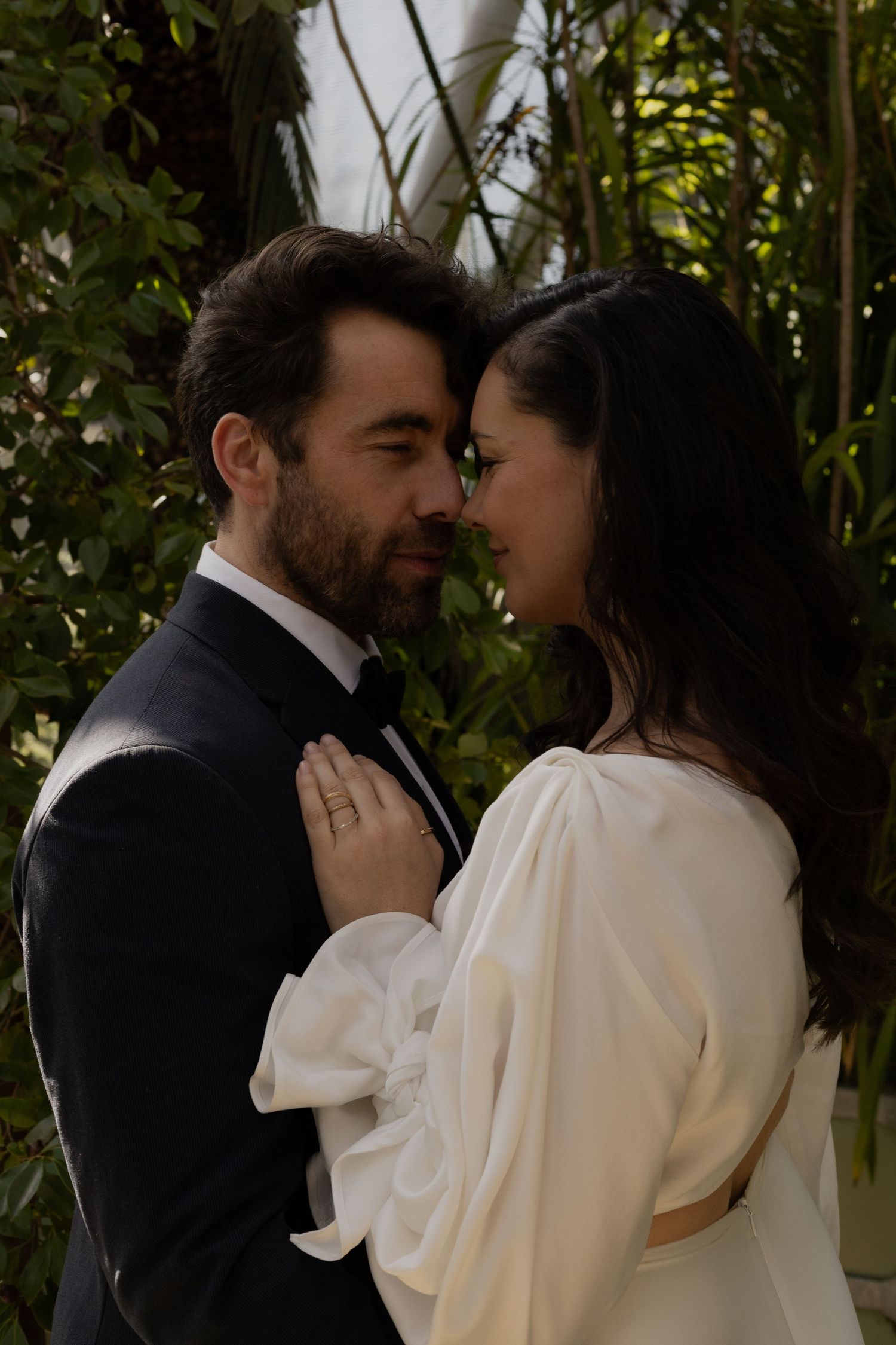 A couple sharing a tender moment in a garden setting with natural greenery.