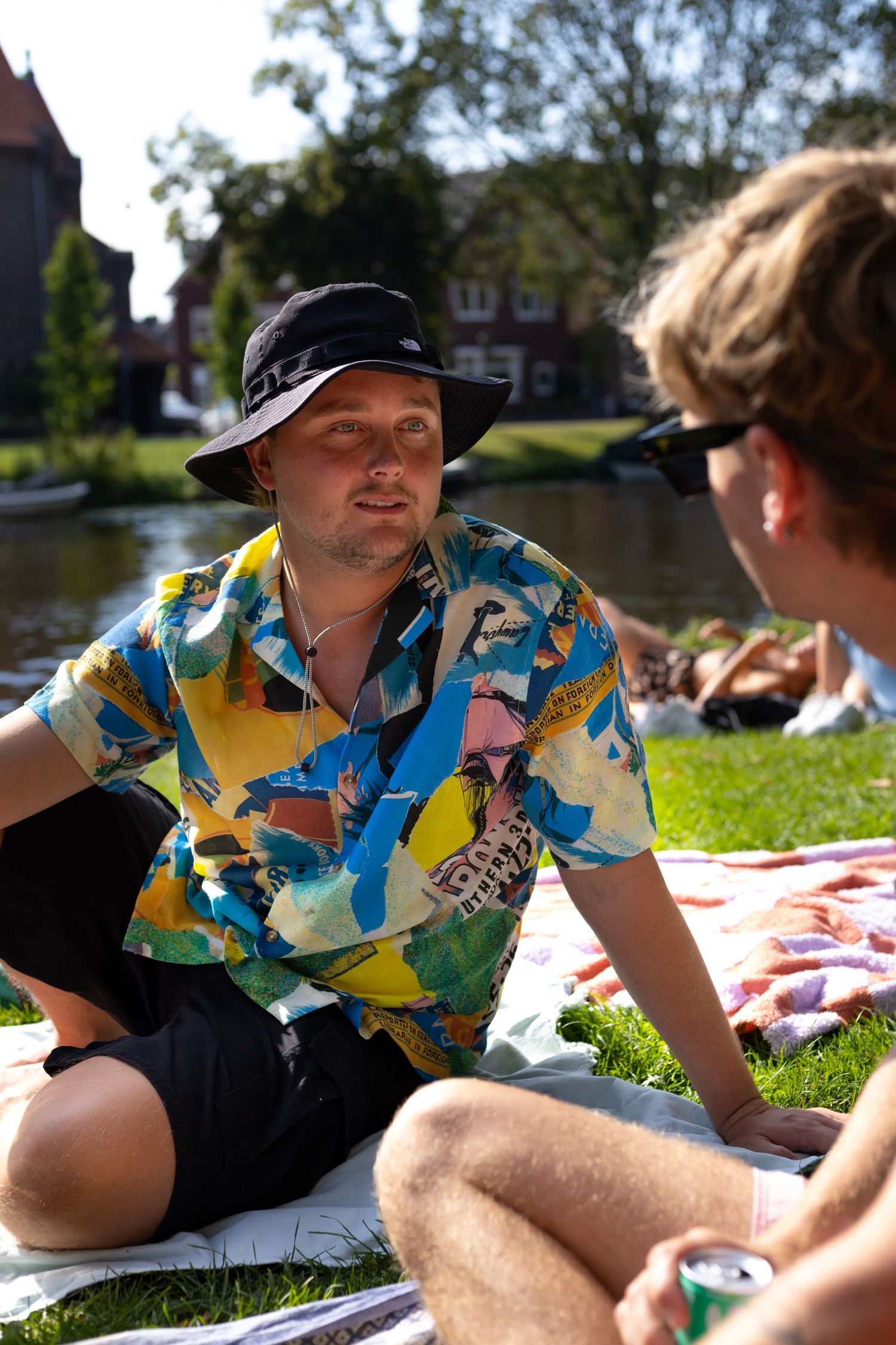 DJ in a colorful tropical shirt performs at an outdoor event on a sunny day.