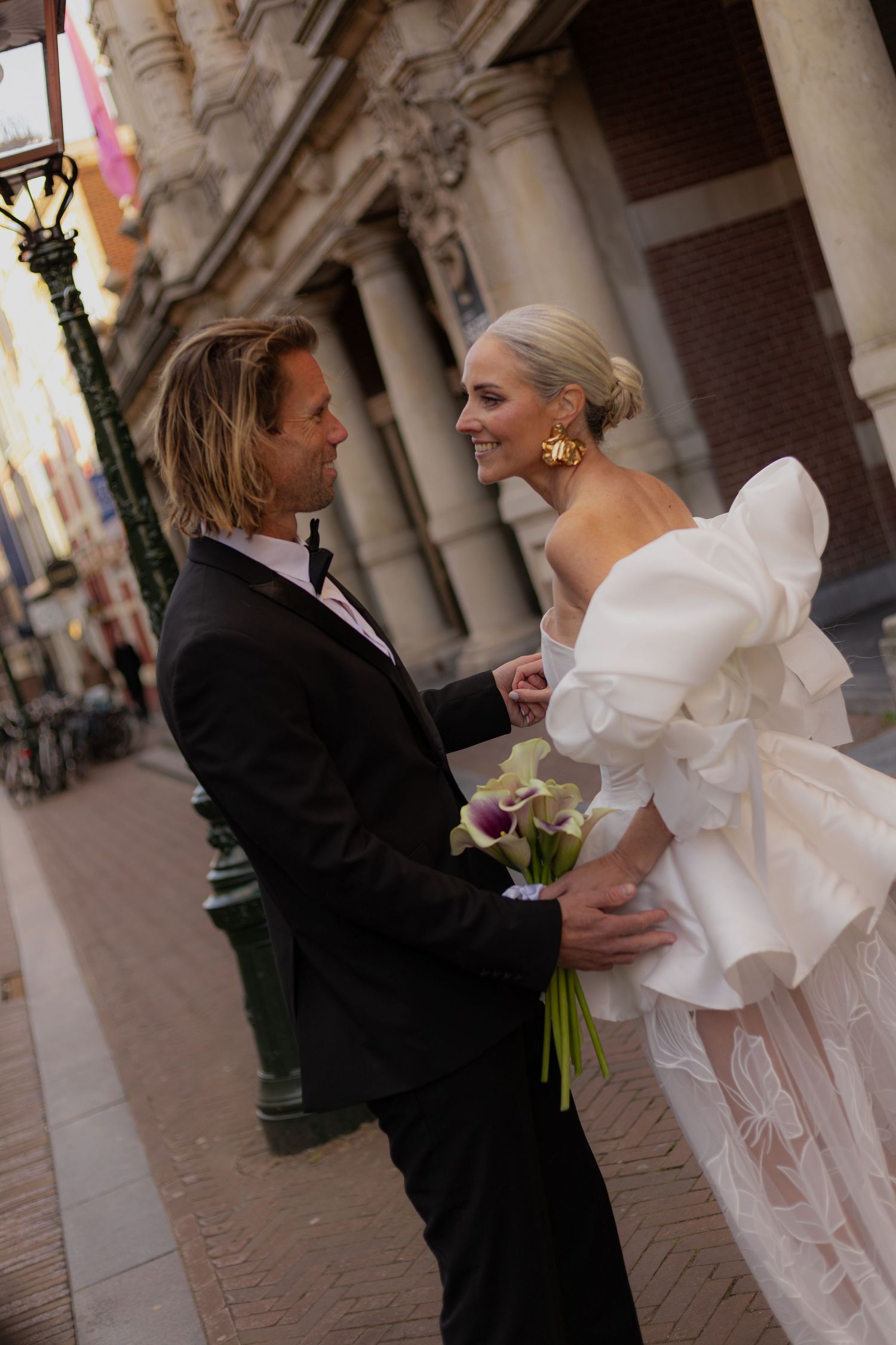 An elegant couple shares a romantic moment under ornate stone columns.