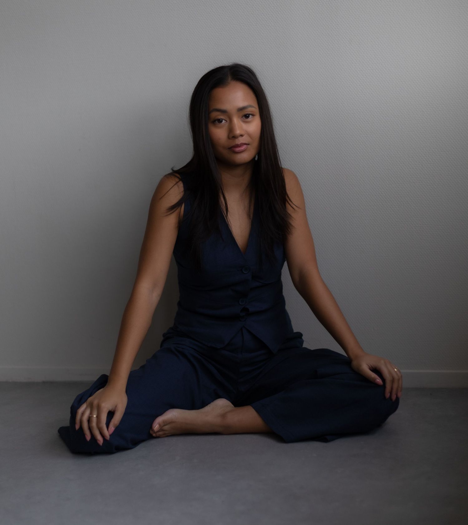 Artistic portrait series of someone in navy outfit against grey background.