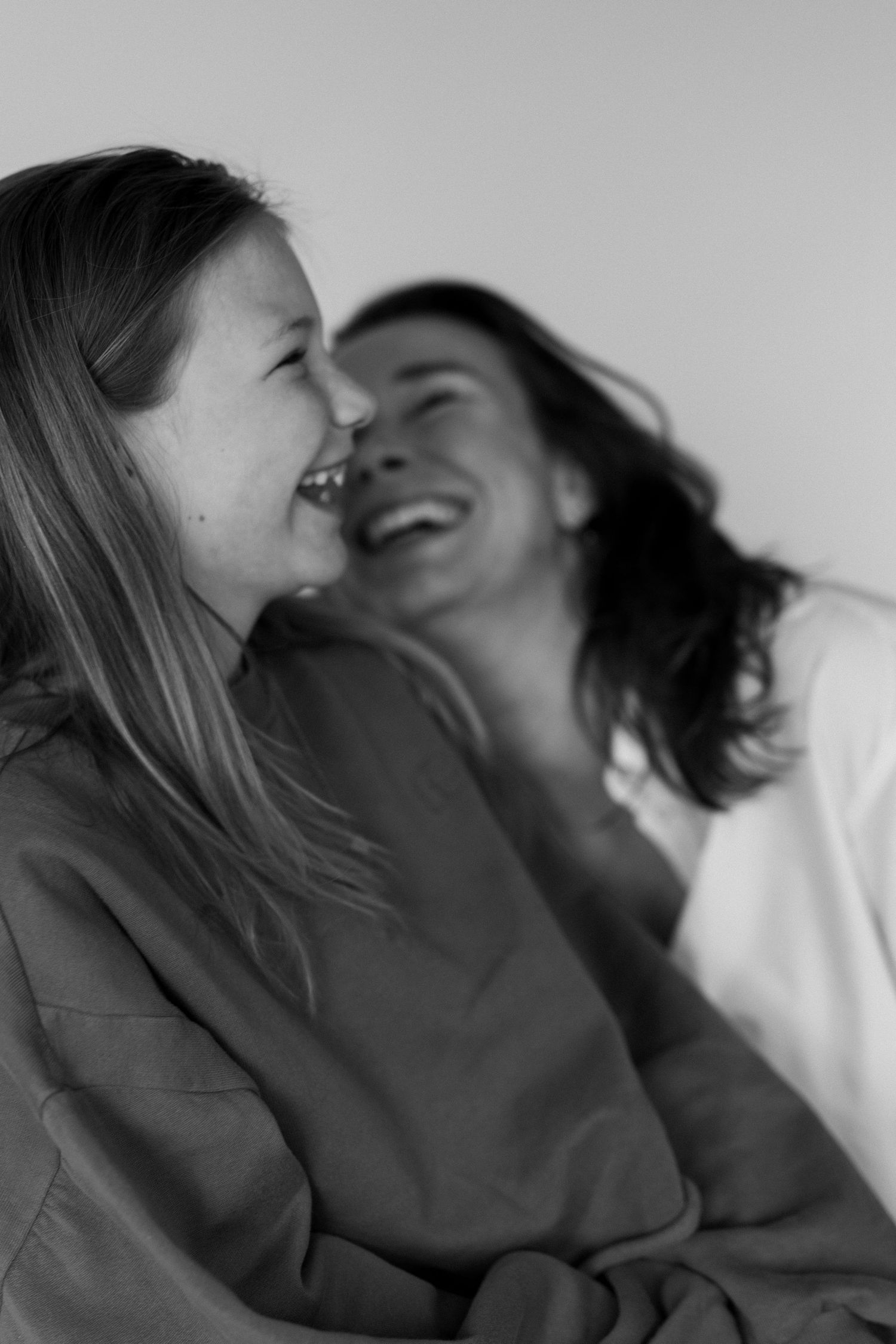 Black and white photo of a laughing girl and woman sharing a joyful moment together.