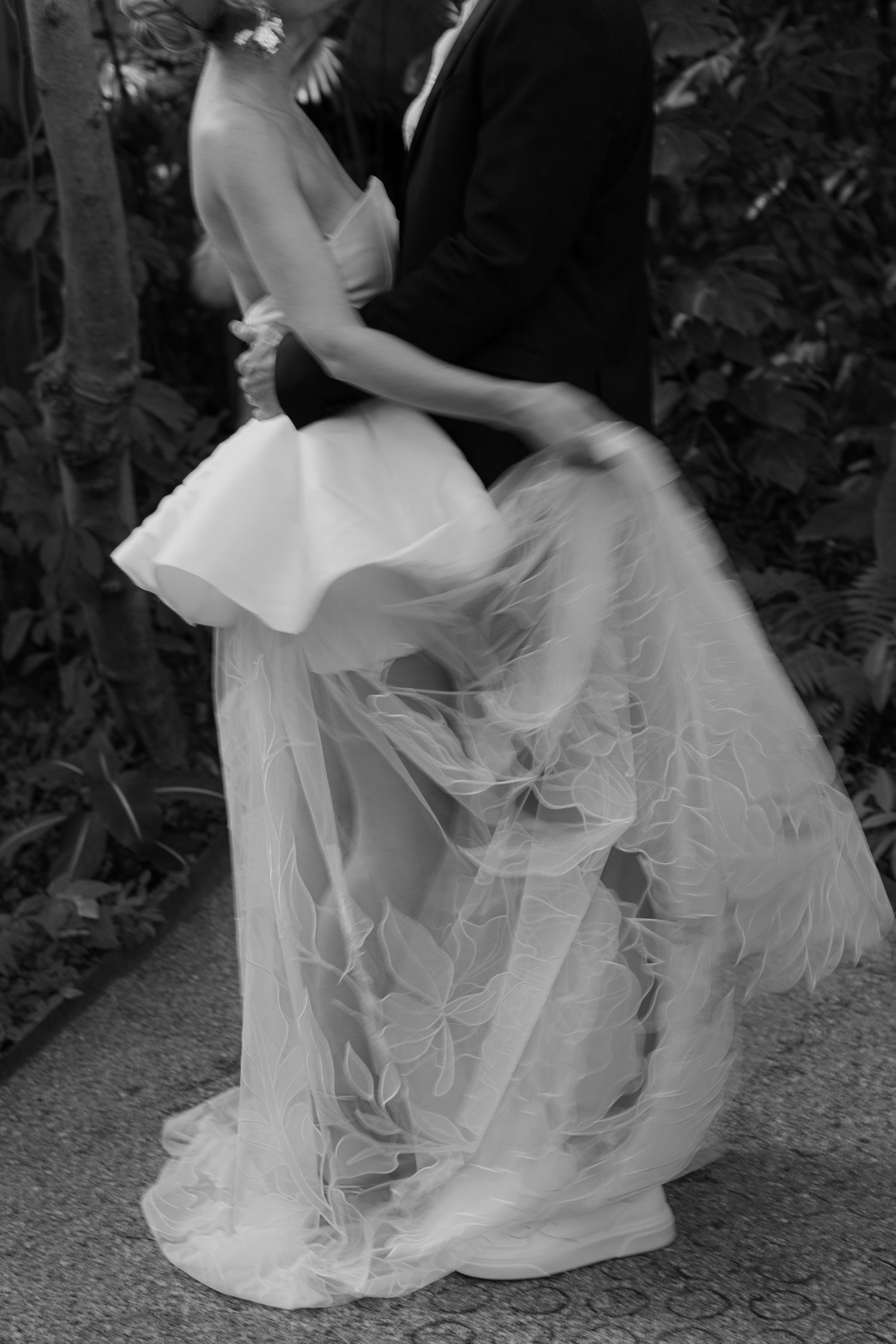 Flowing layers of white tulle and fabric create movement in a wedding dress.