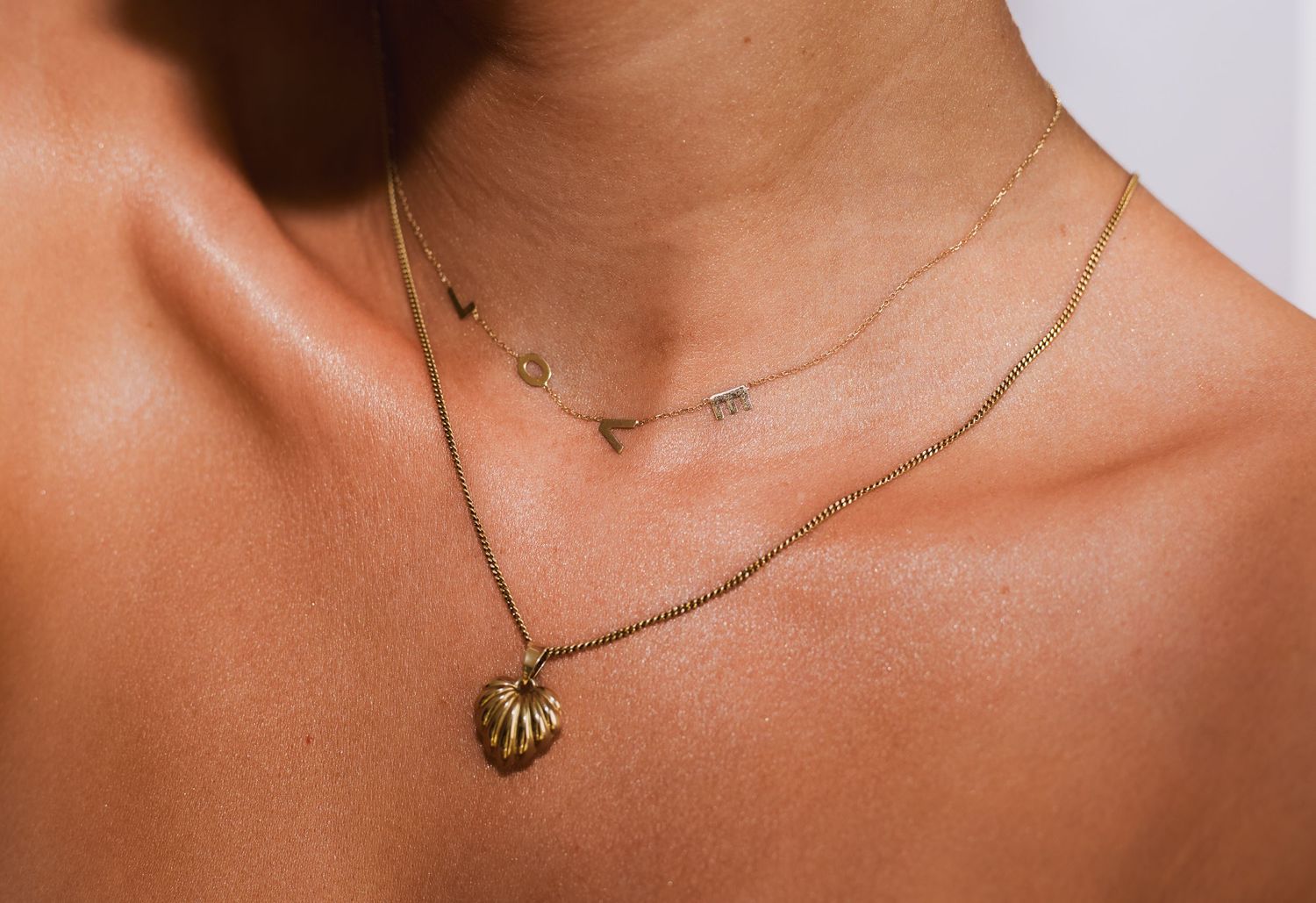 Close-up view of a delicate gold necklace with minimalist design against warm skin tones.
