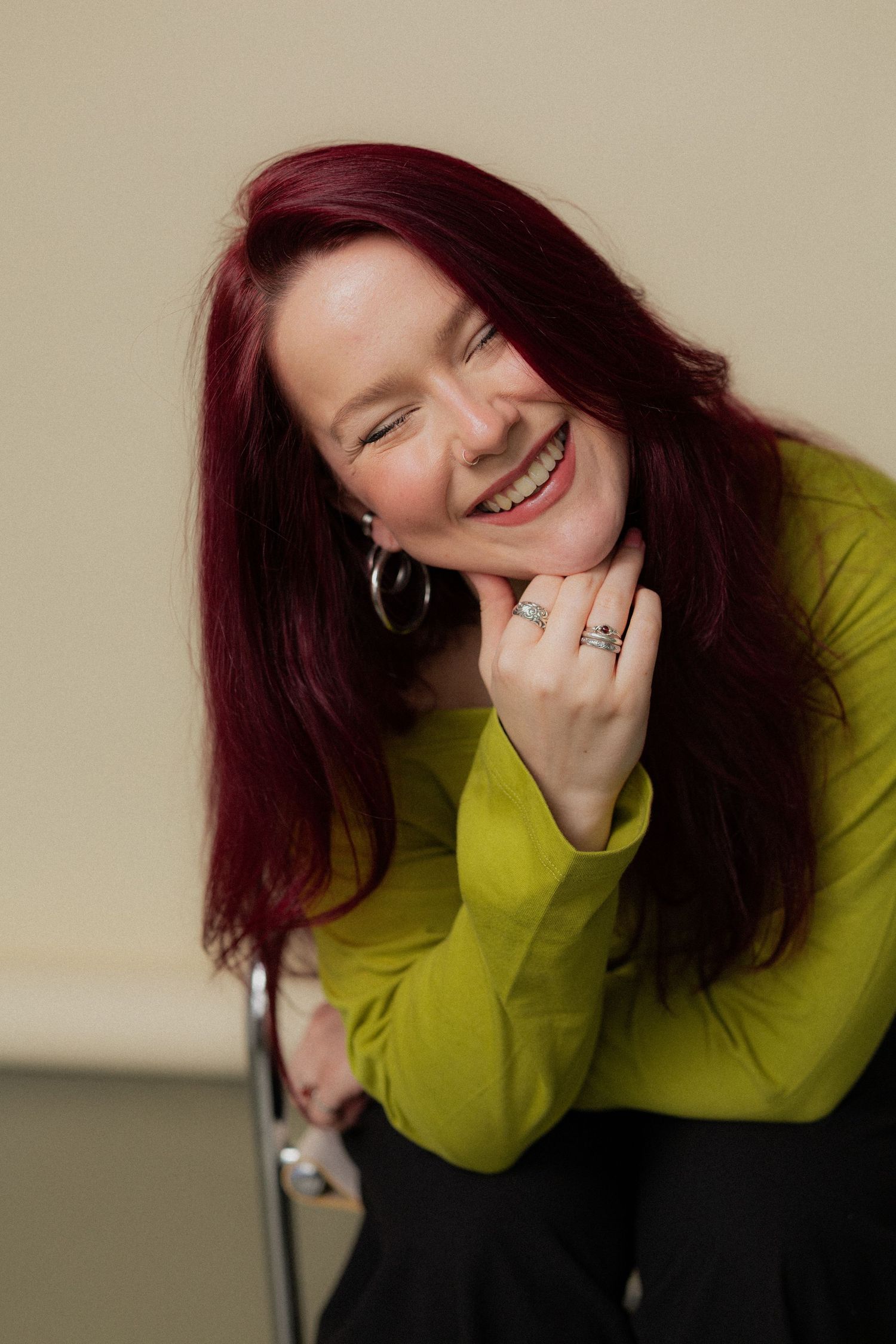 A person with vibrant red hair wearing a lime green sweater poses playfully in a sequence of candid portrait shots.