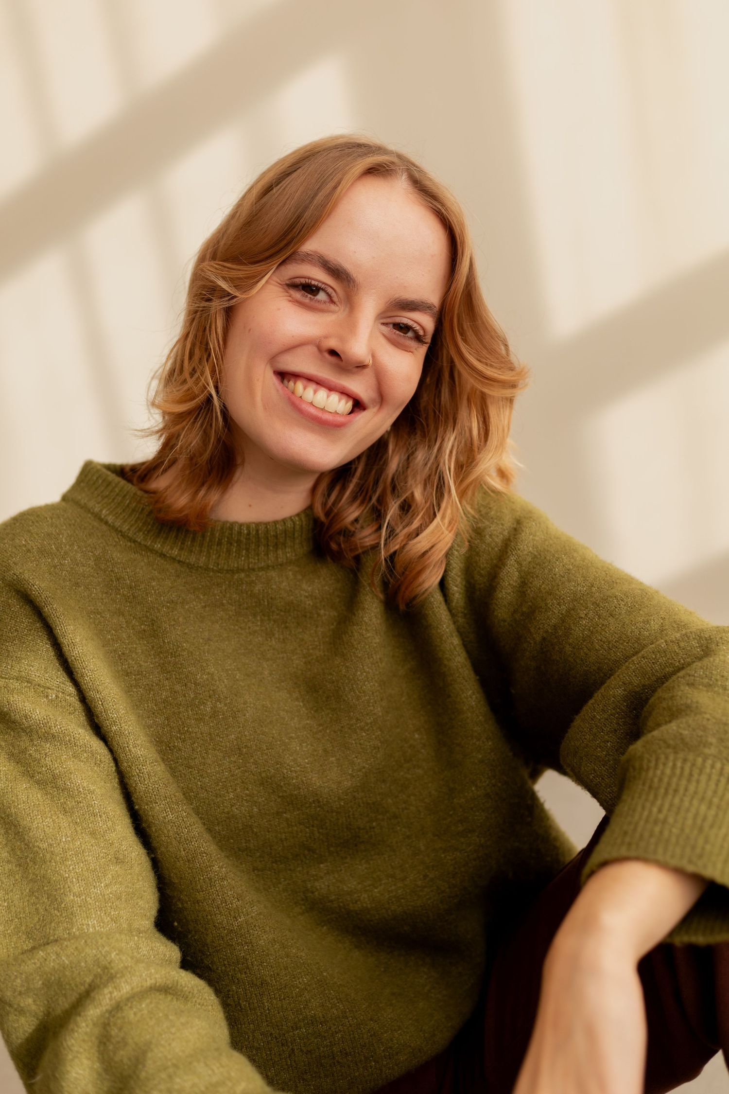 A series of photos showing someone wearing a cozy olive green knit sweater in warm natural lighting.