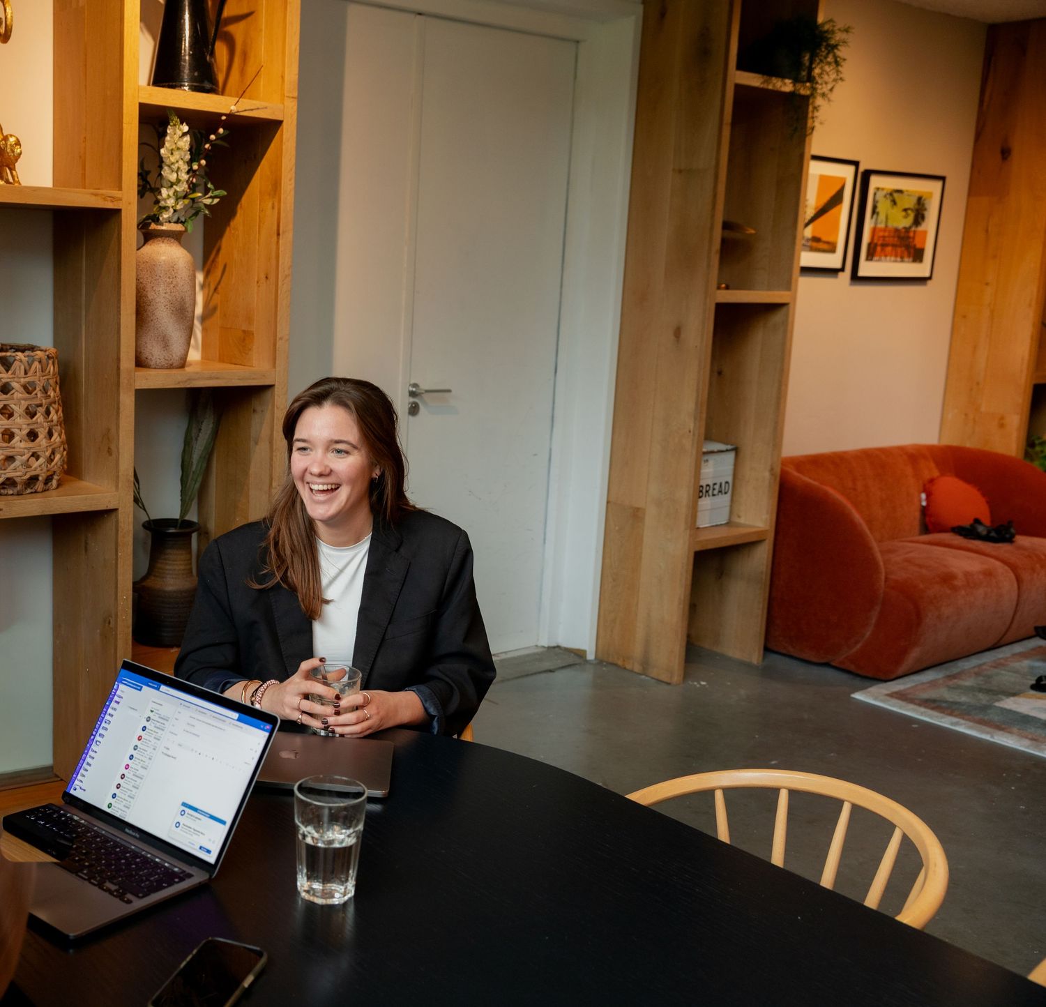 Business professionals collaborating at a wooden table in a modern office space with built-in shelving.
