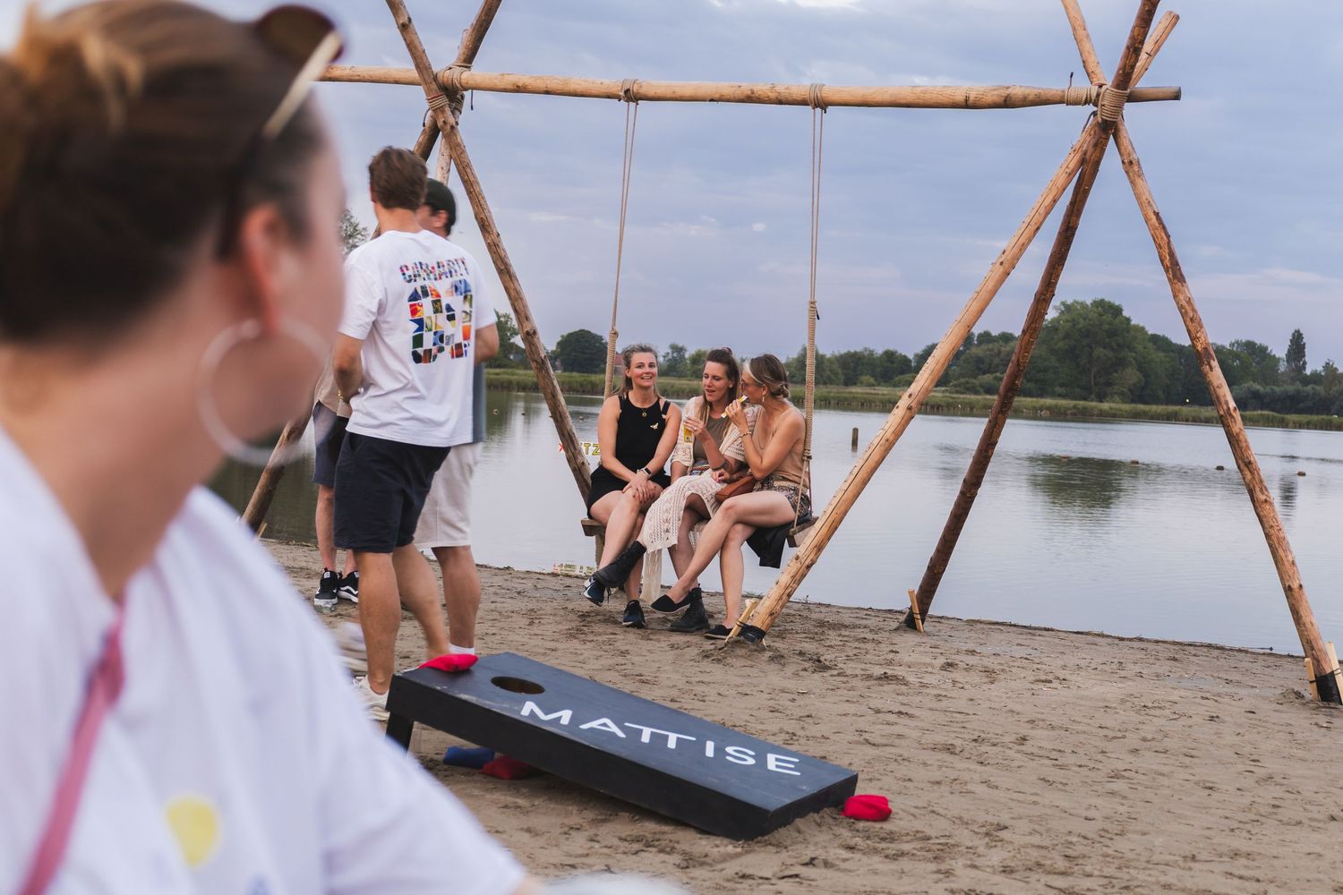 Wooden structure on a beach with people relaxing in the background.