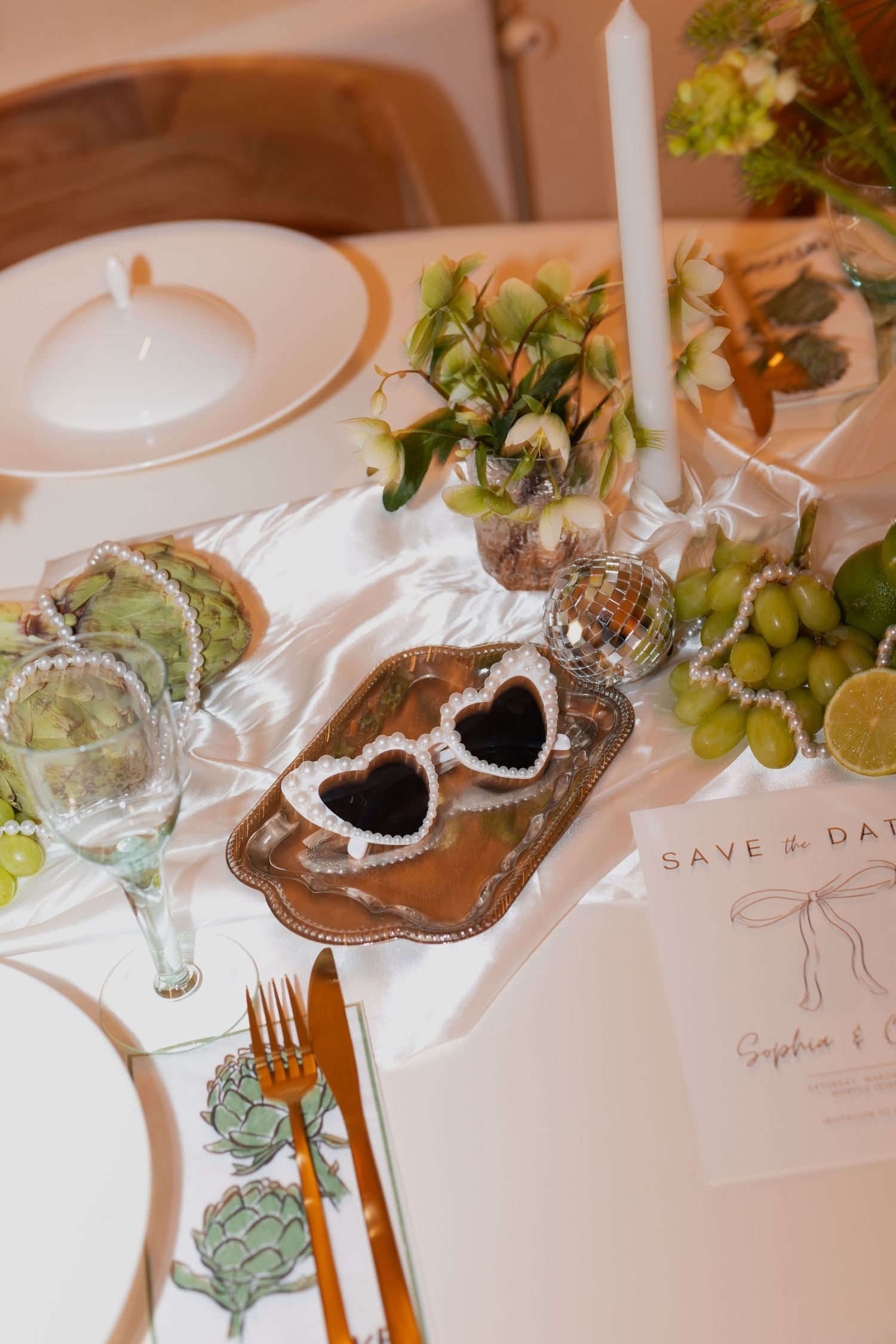 Wedding table decor featuring heart-shaped details, candles, and green accents.