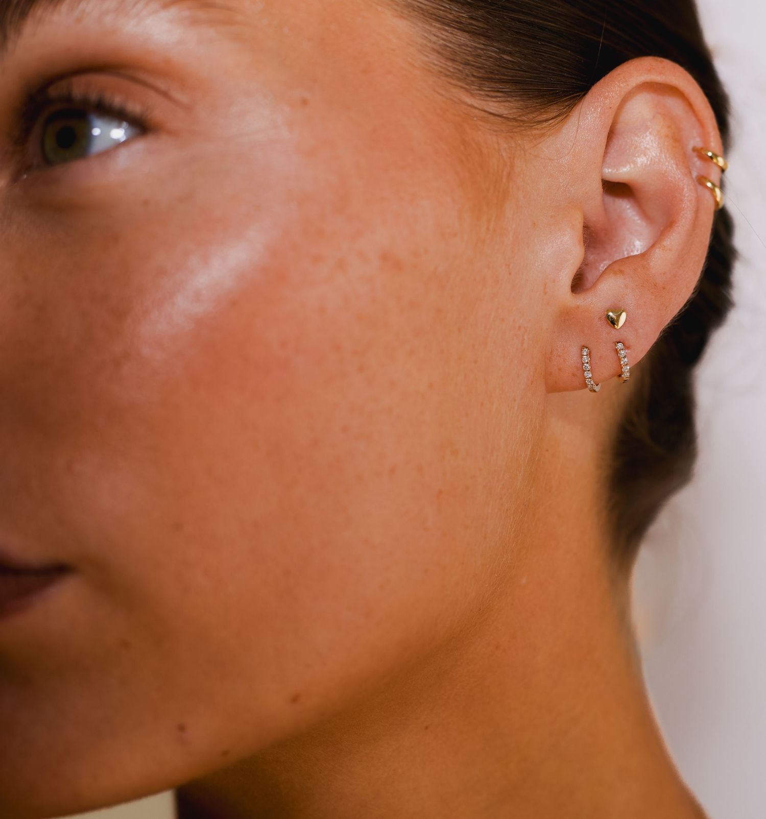 Profile view showcasing multiple small ear piercings with minimalist jewelry.