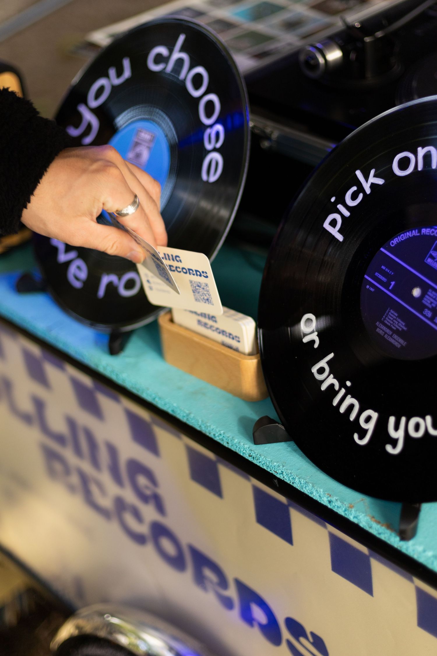 Close-up of vinyl records with custom blue text labels on display at a market stall.