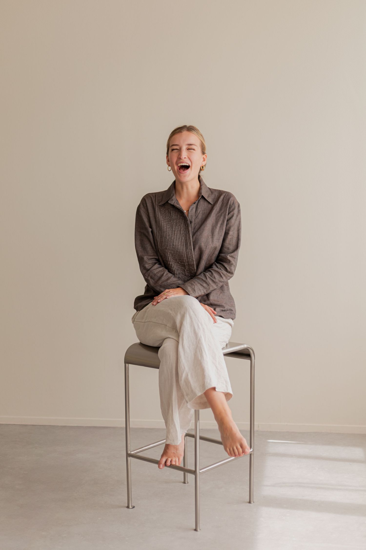 Sequence of minimalist photos showing someone in casual attire sitting on a modern gray chair making playful poses.