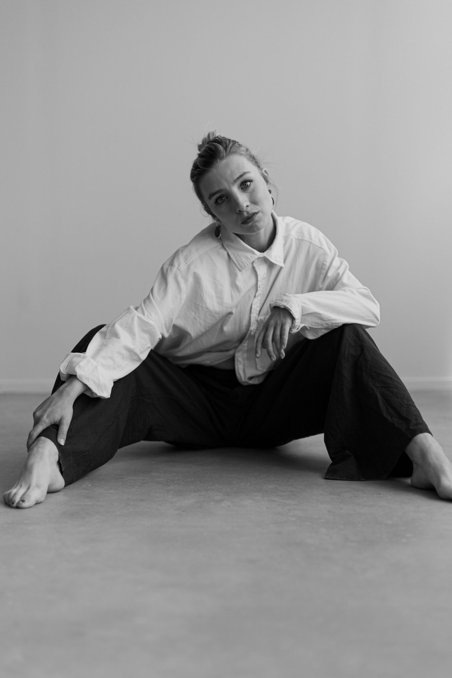 Black and white photo series of someone in white shirt and dark pants posing on the floor.