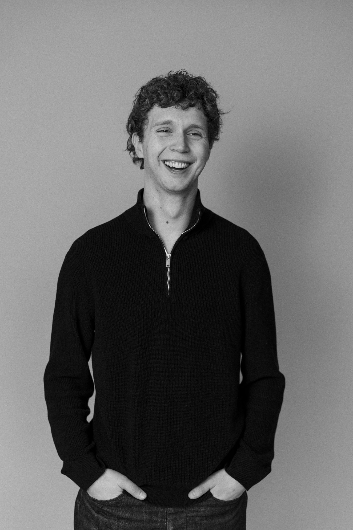 Black and white portrait series showing a person in dark clothing against a light background, expressing joyful emotions.