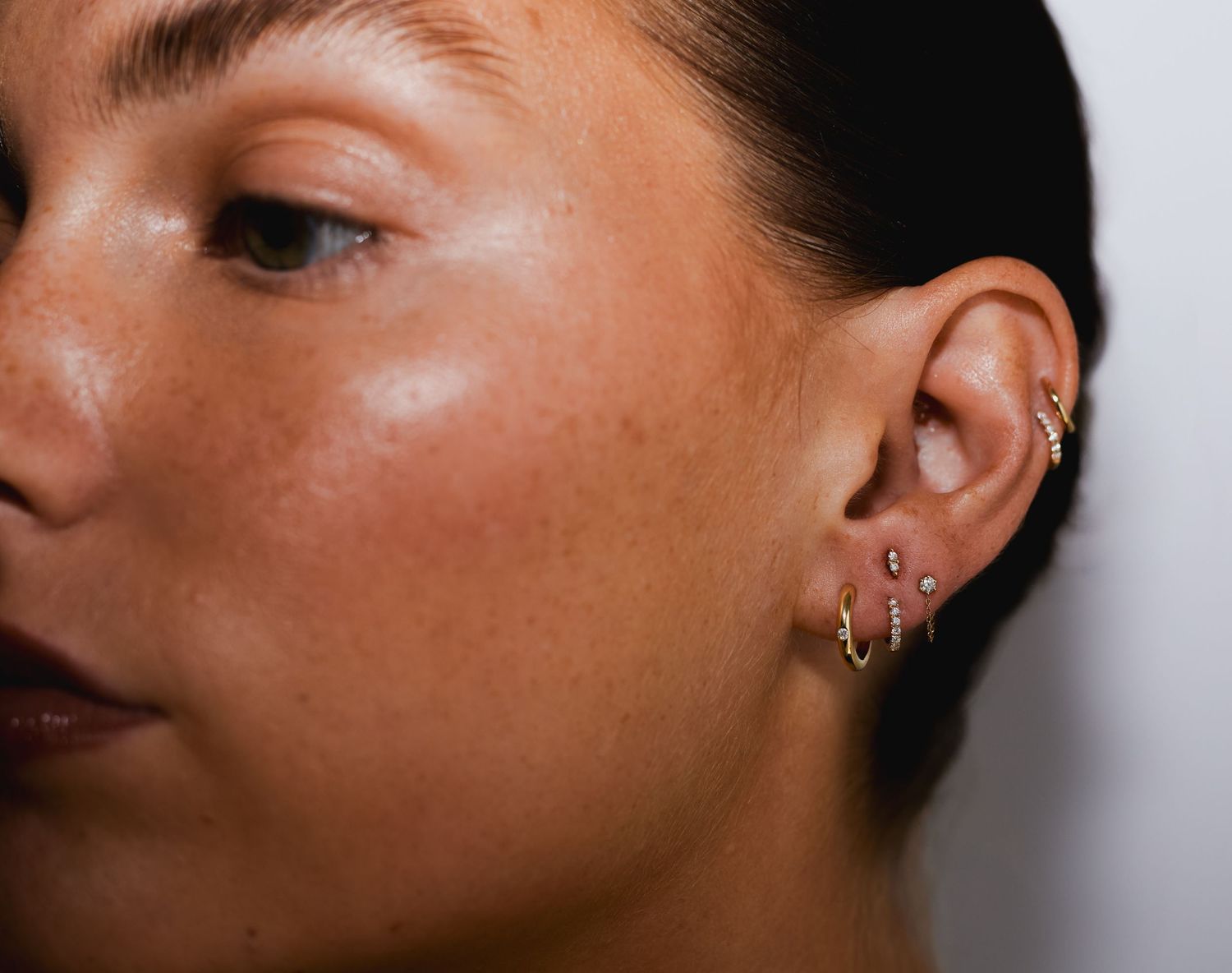 Close-up detail of ear piercings with small gold stud earrings.