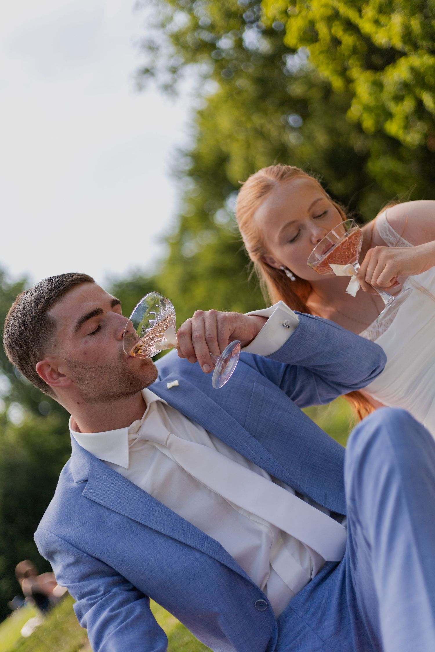 A couple takes celebratory drinks outdoors on their wedding day.