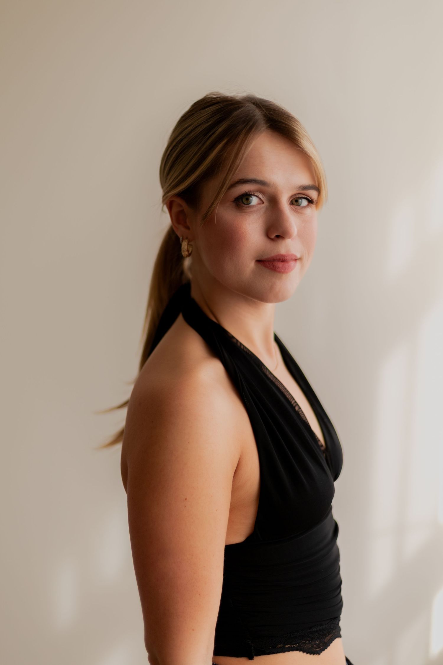 Portrait series of someone wearing a black sleeveless top against a white background with dramatic lighting.