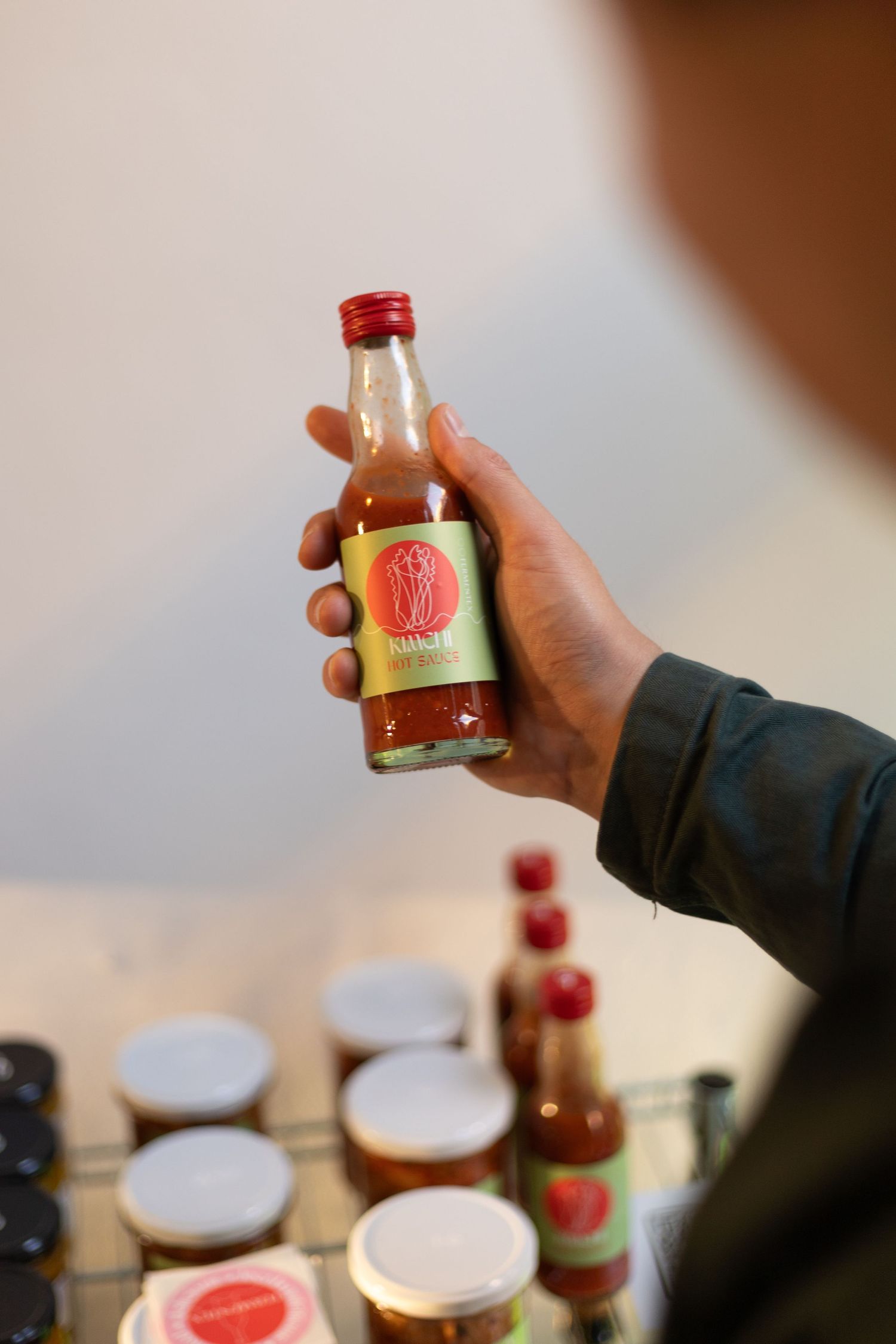Hand holding small glass bottles with red caps against blurred background.