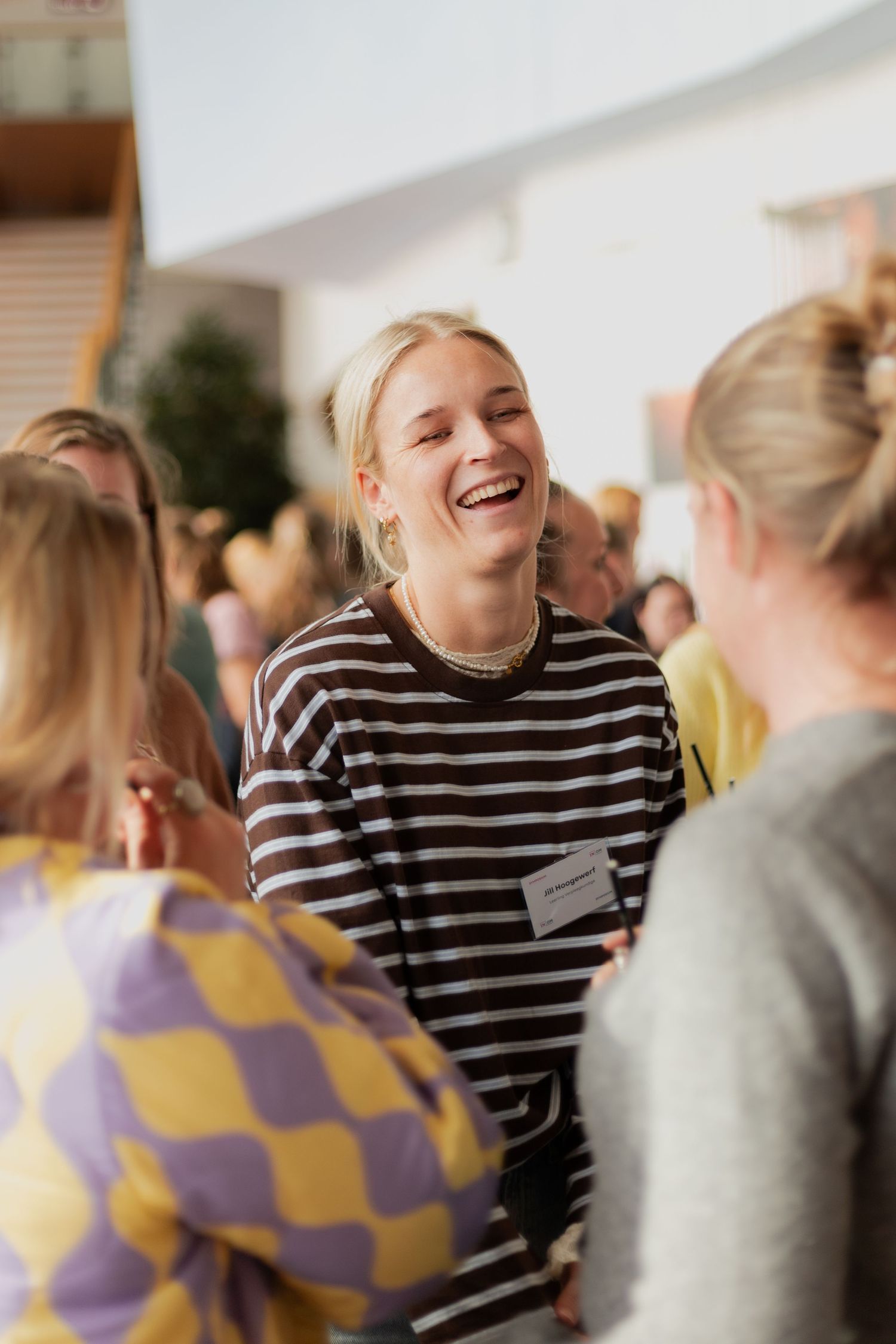 People engaged in lively conversation at a social gathering, with one wearing a black and white striped shirt.