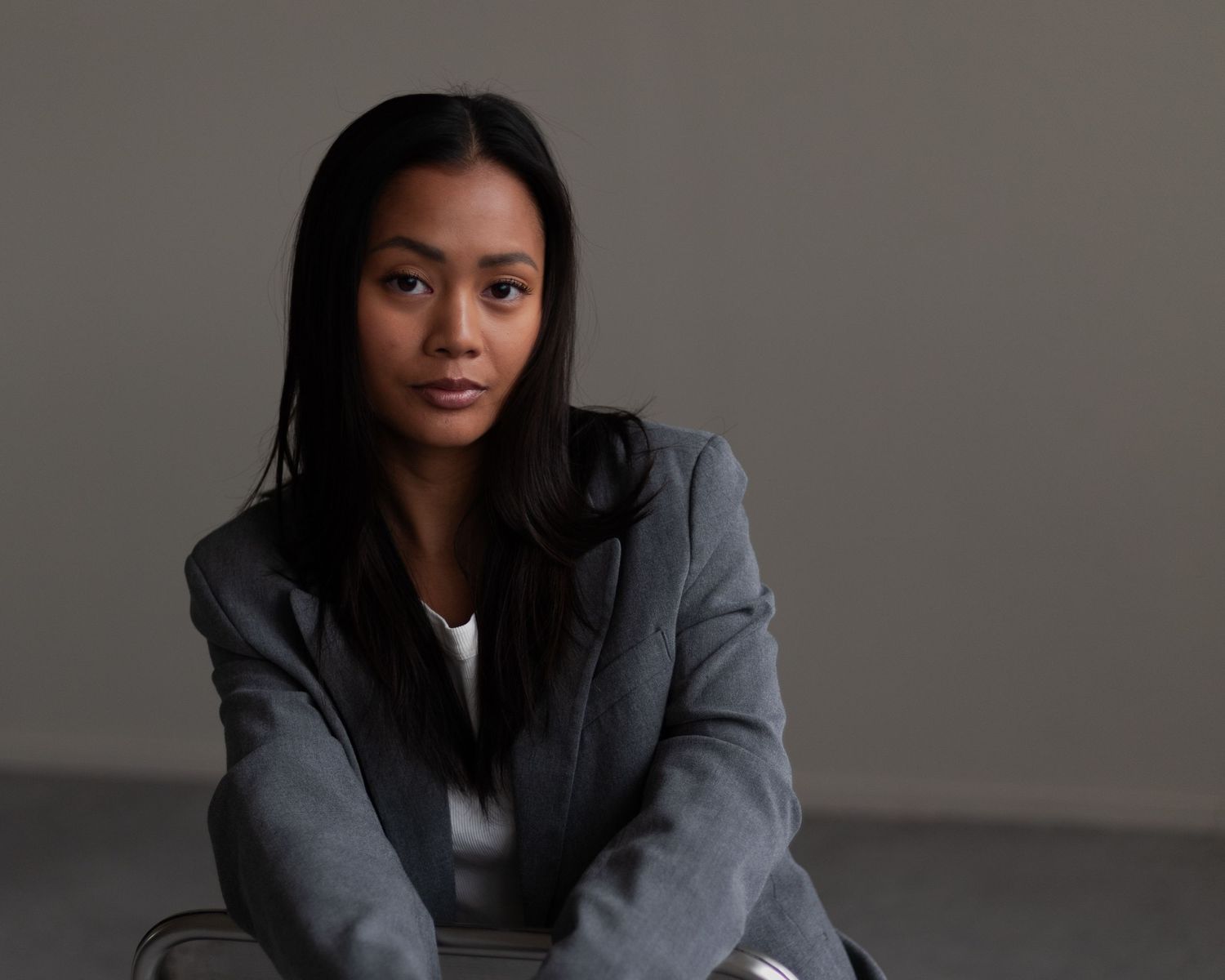 Professional studio portrait in business attire against dark gray background.