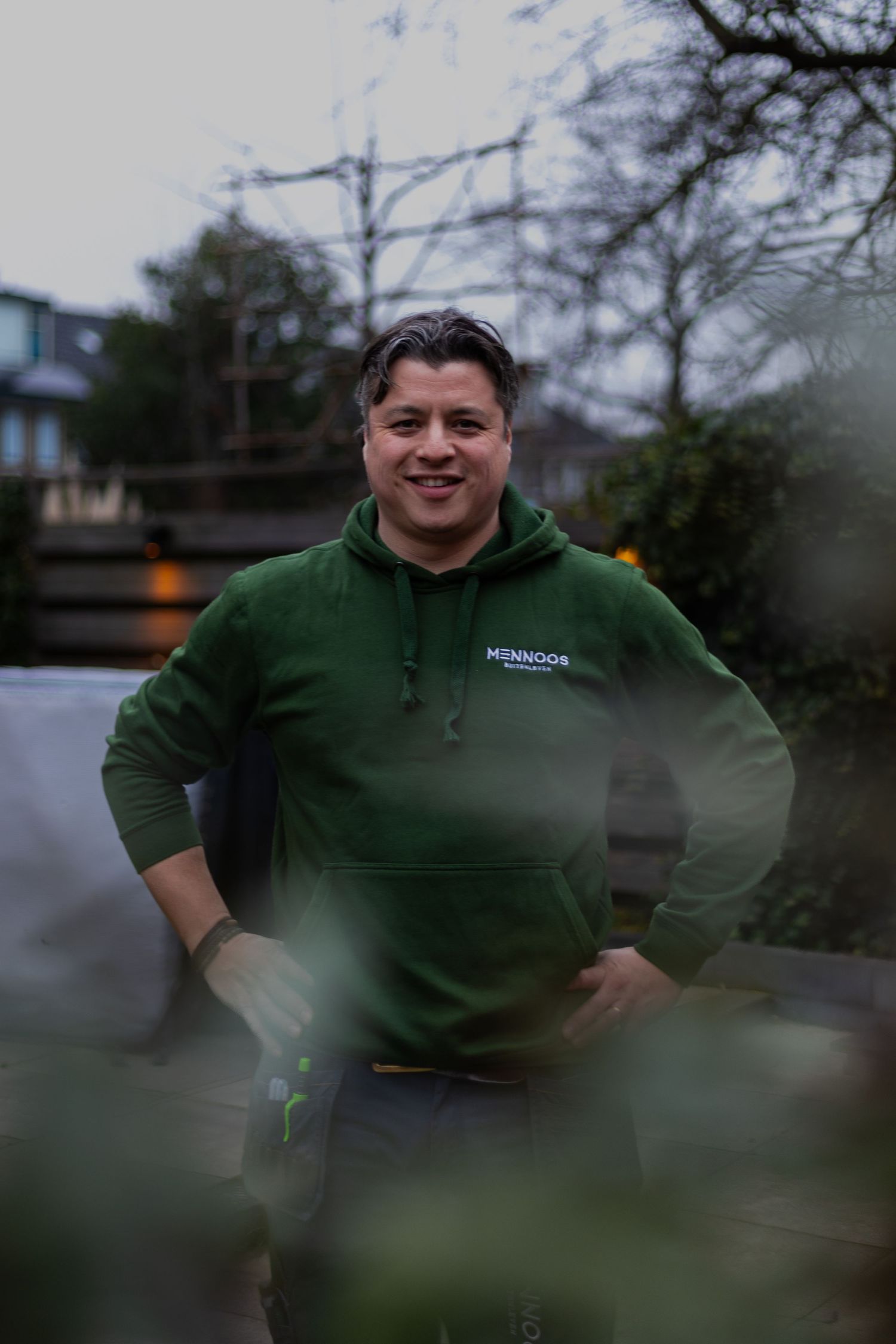 Someone wearing a green hoodie standing outdoors at dusk.