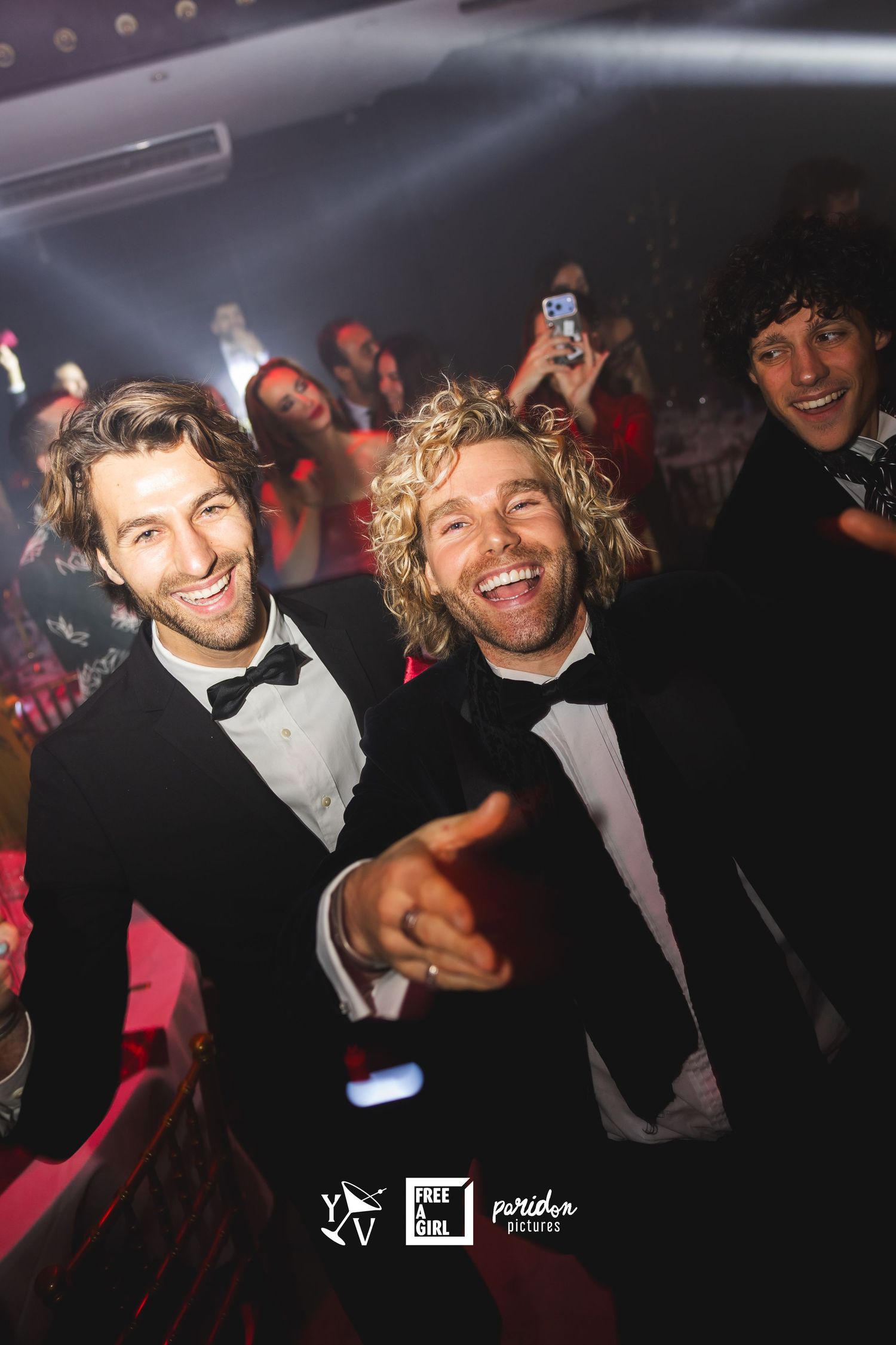 Partygoers enjoying themselves at a formal nighttime event with dark lighting and festive atmosphere.