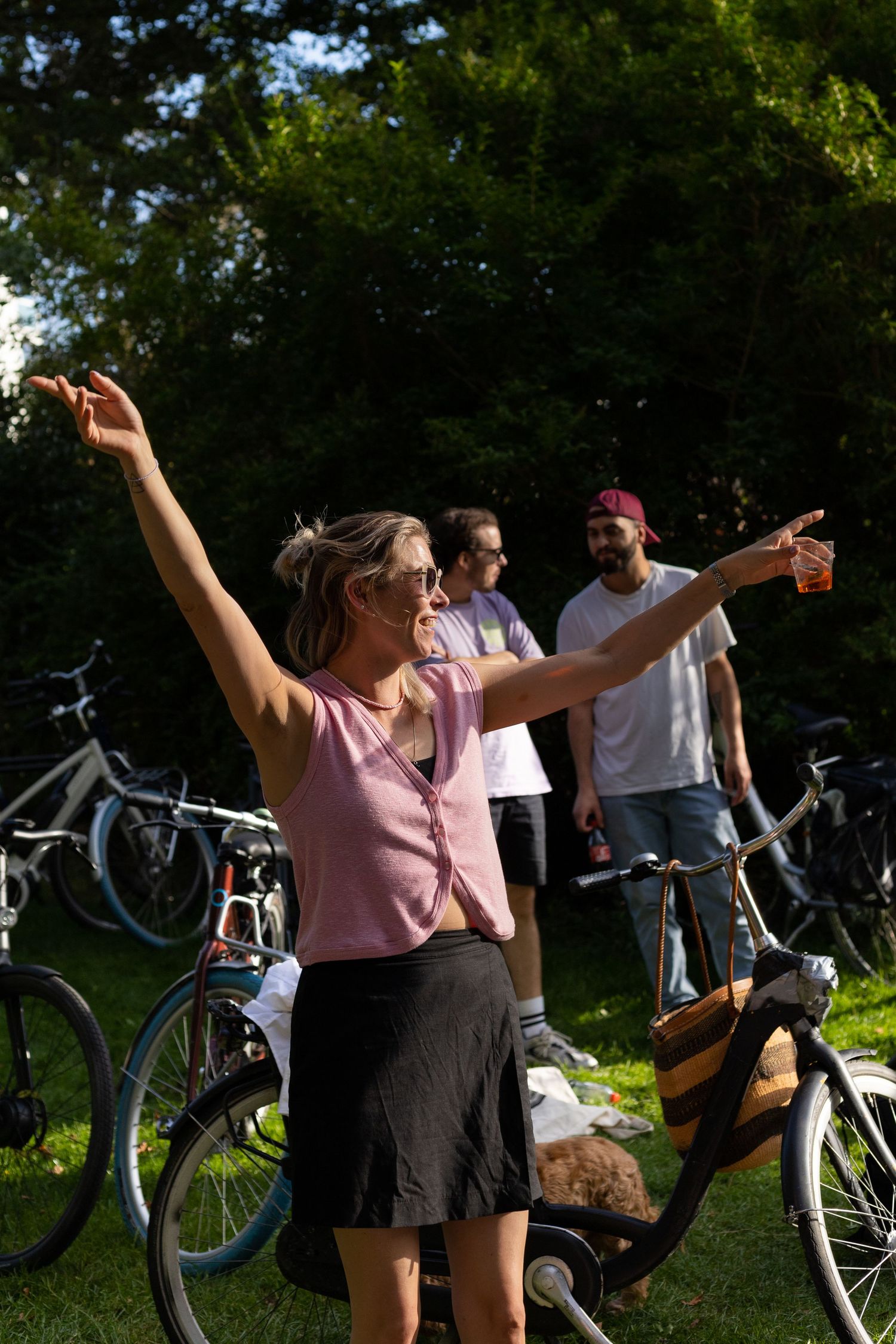 People dancing and raising their arms during an outdoor party with bicycles in background.