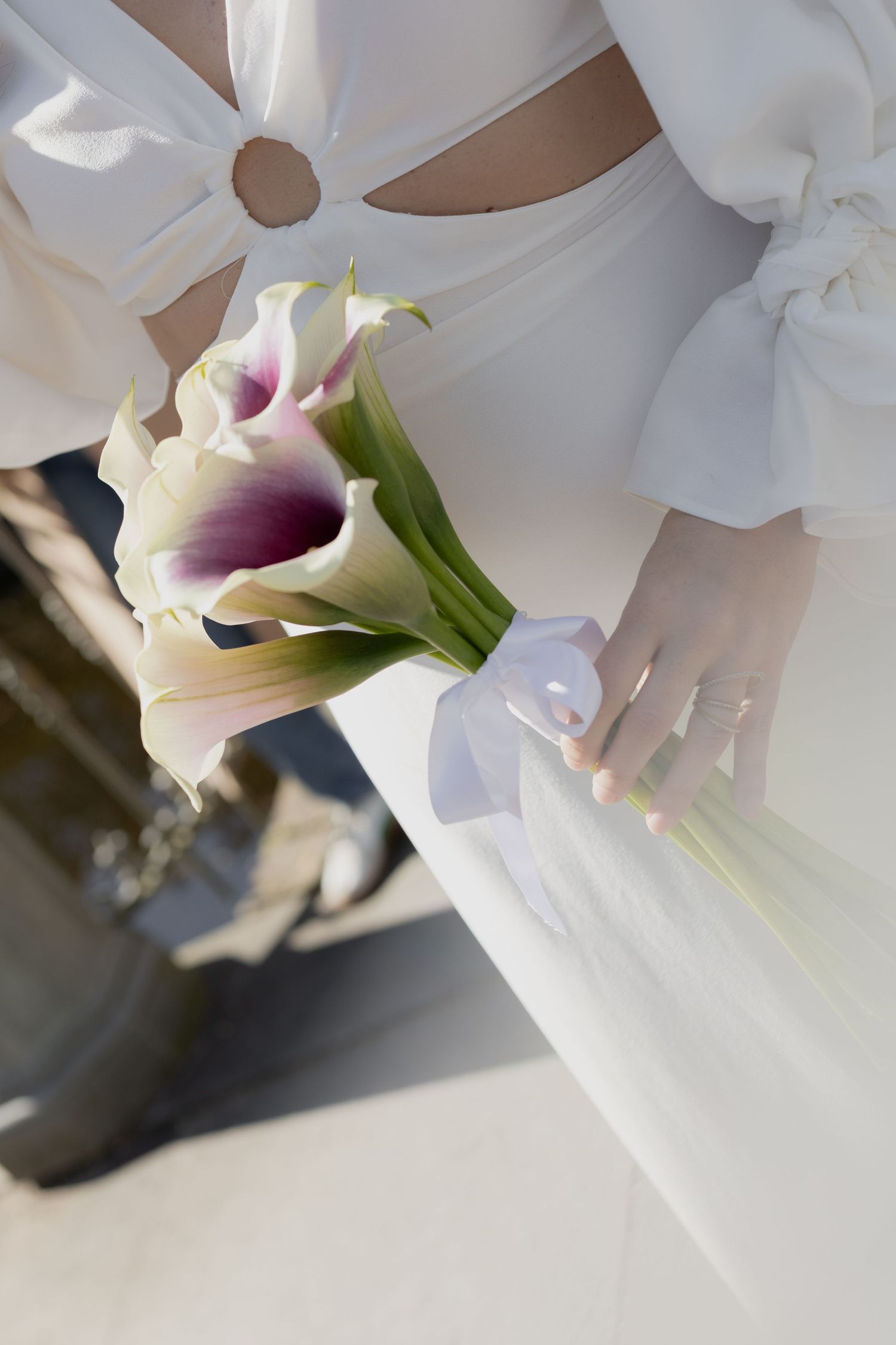 Close-up of white calla lilies in a bridal bouquet with delicate fabric details.