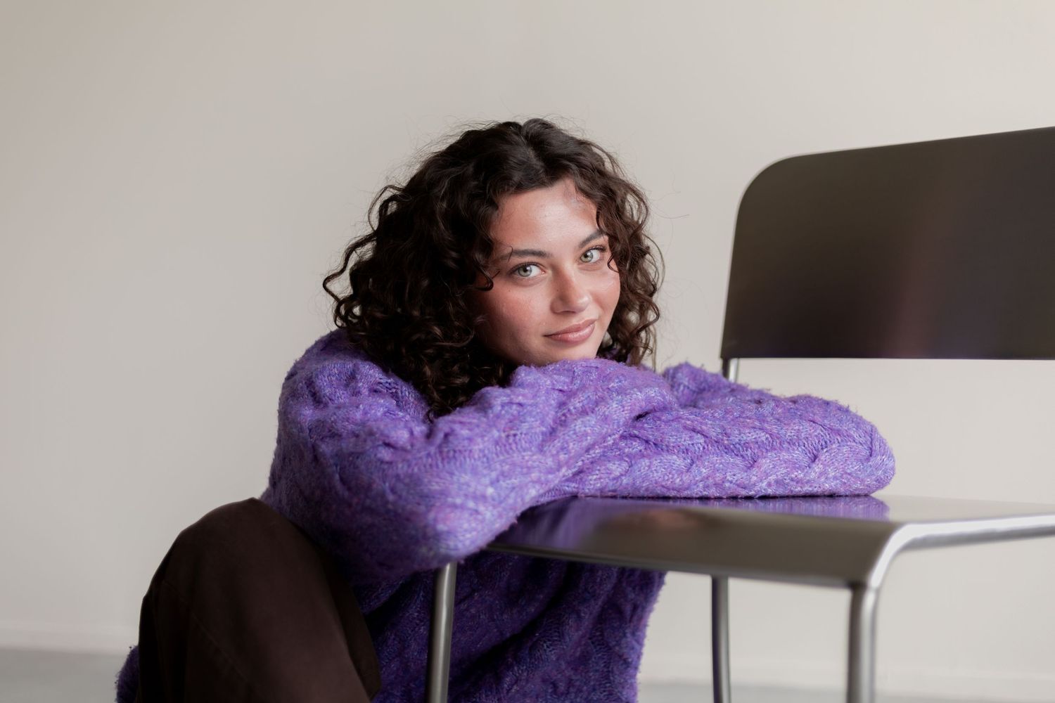 A person wearing a cozy purple knit scarf sits at a desk in an office setting.