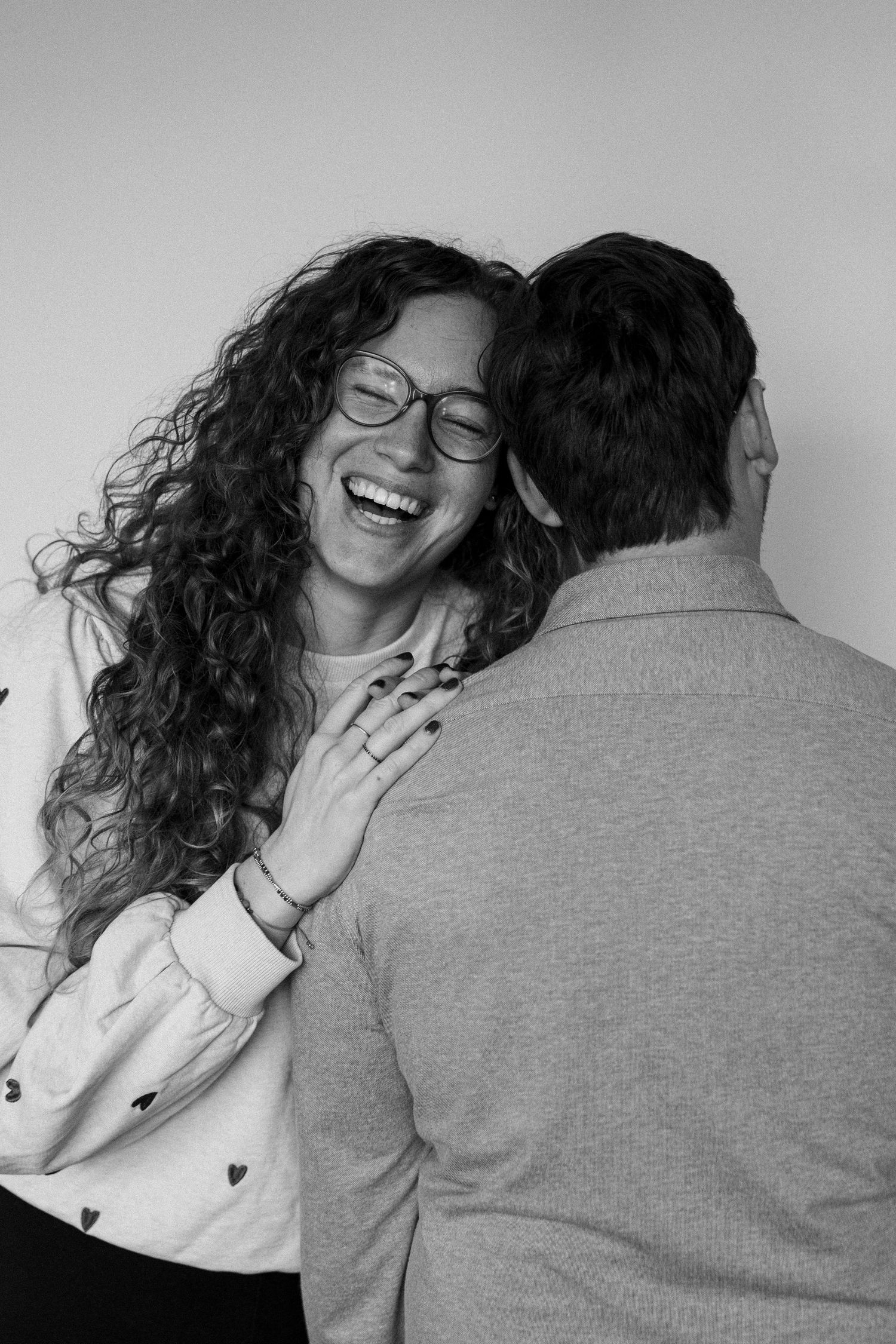 A series of black and white photos showing a couple embracing and laughing together in candid moments.