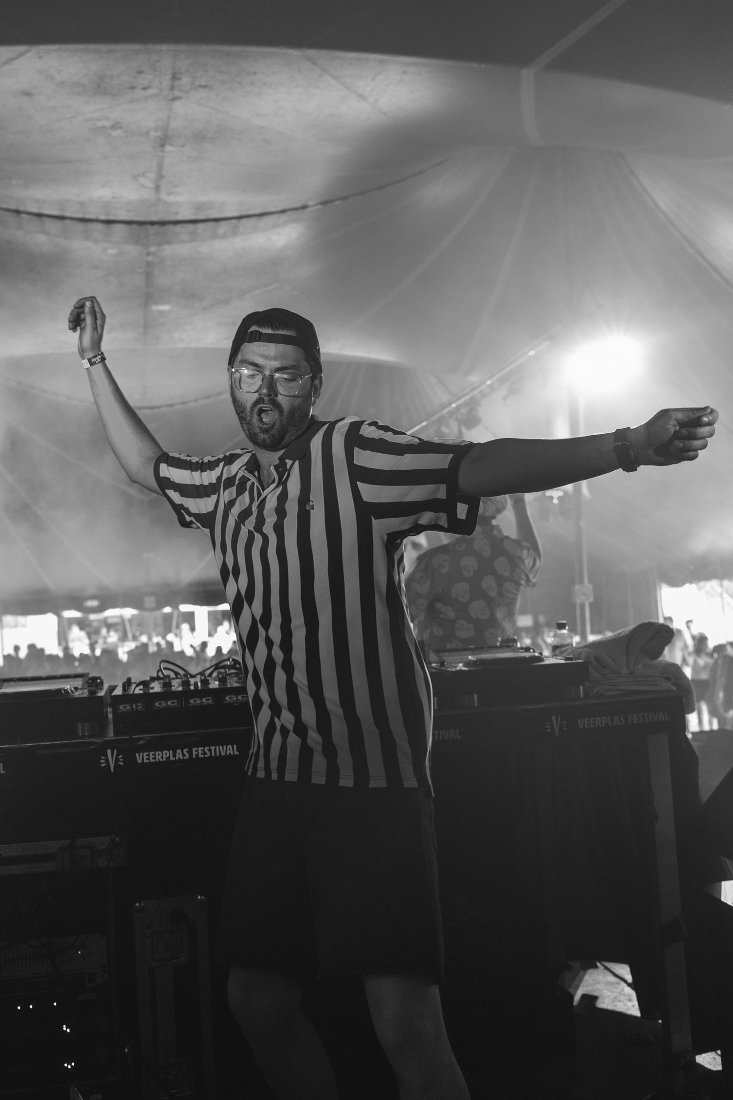 Person in striped referee outfit performing on stage with dramatic lighting effects.