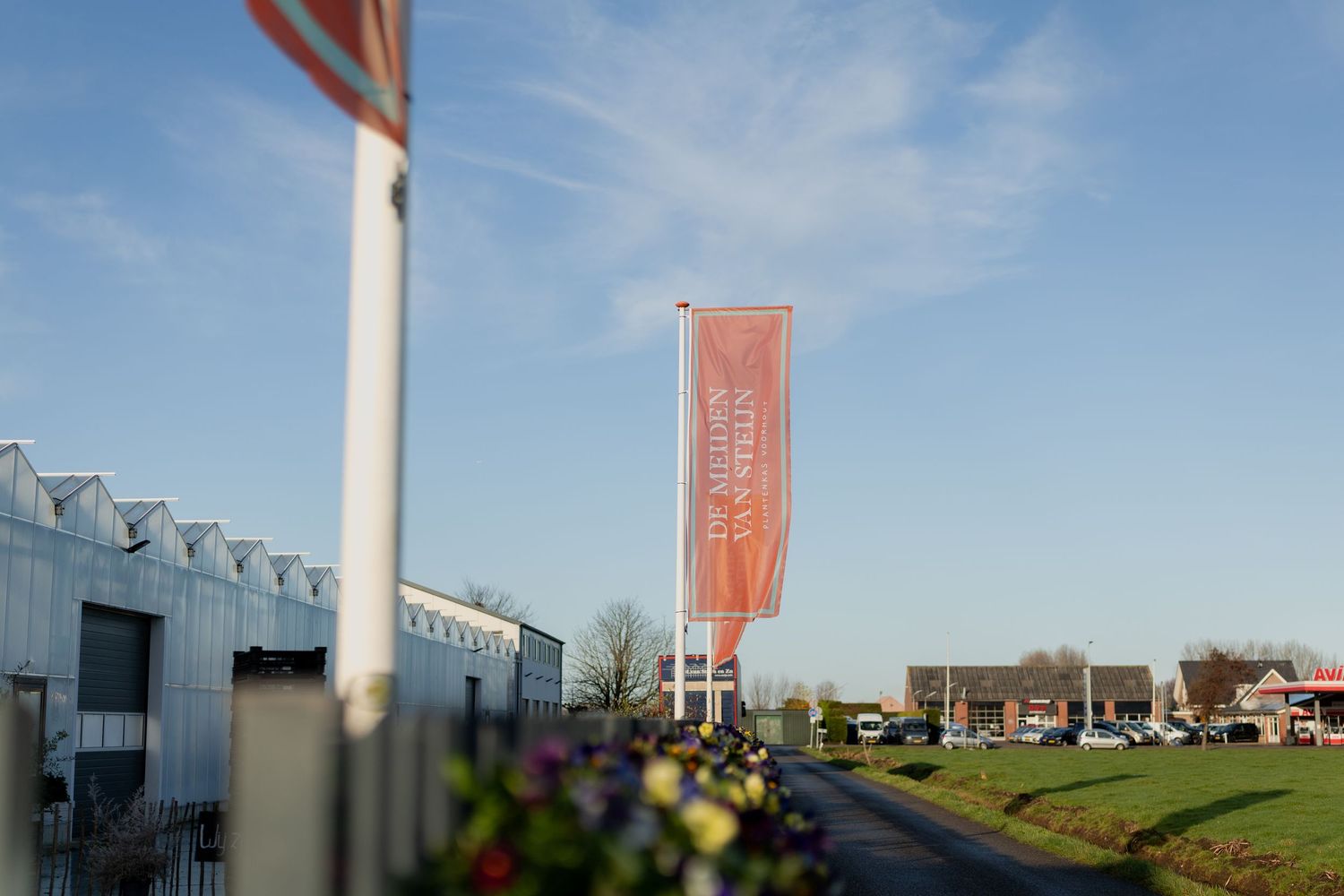 Wind turbines stand tall against a blue sky with industrial buildings and red banners visible in the landscape.