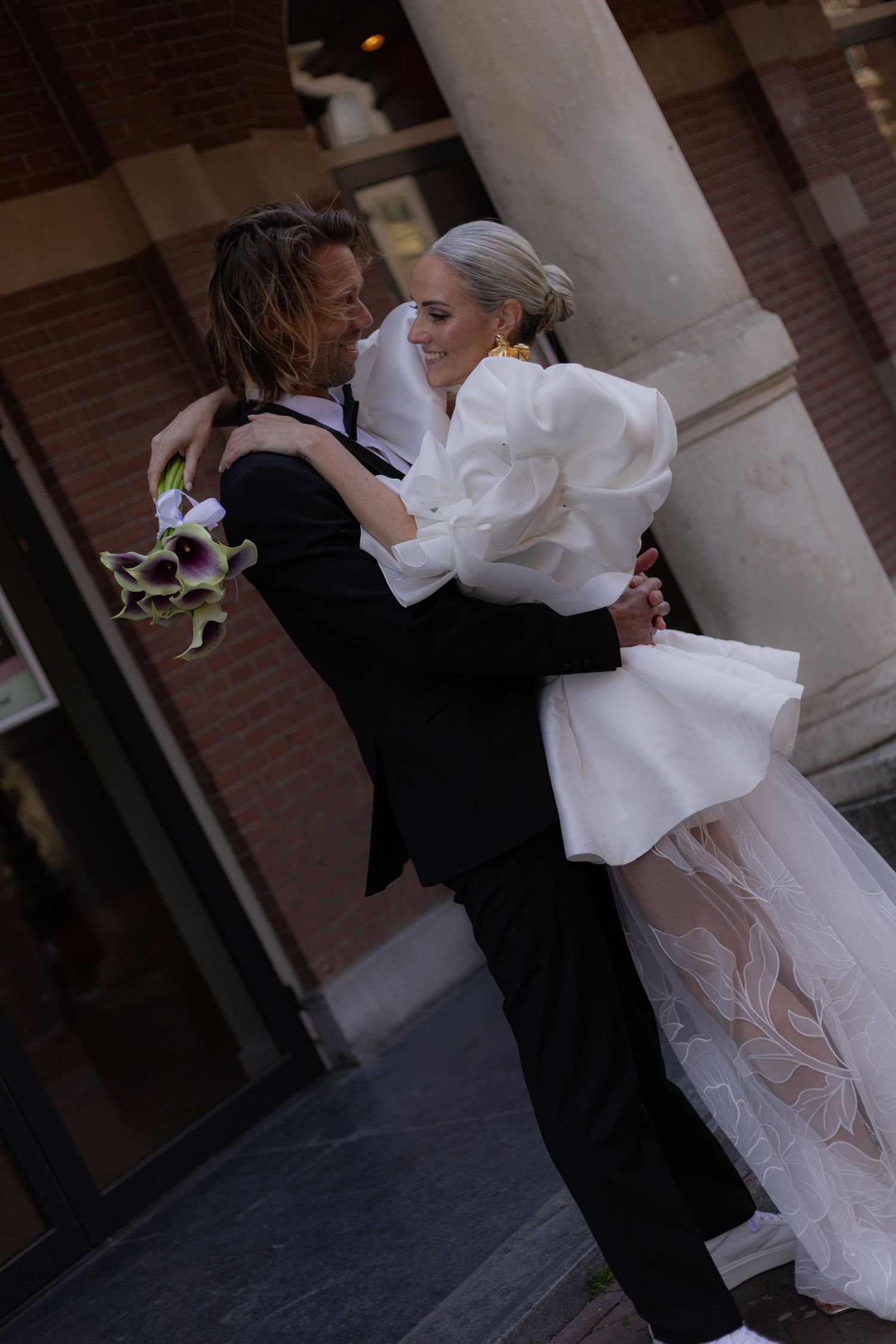 Romantic wedding couple dancing together under classic brick archways.