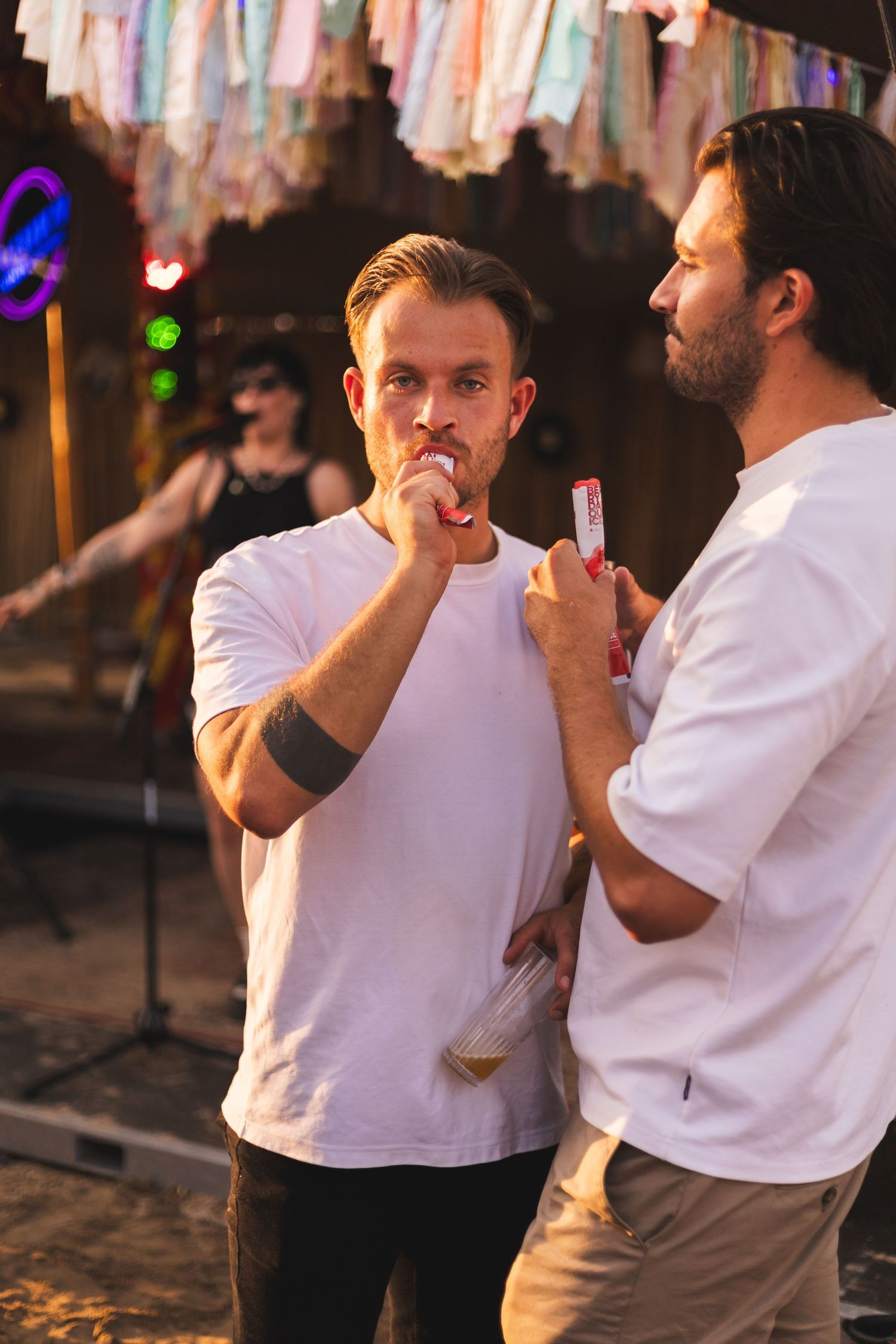 Two people in white t-shirts dancing together at an outdoor party.