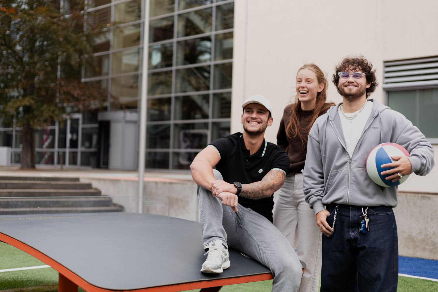 Group of friends sitting on outdoor steps at a college campus laughing and chatting together.