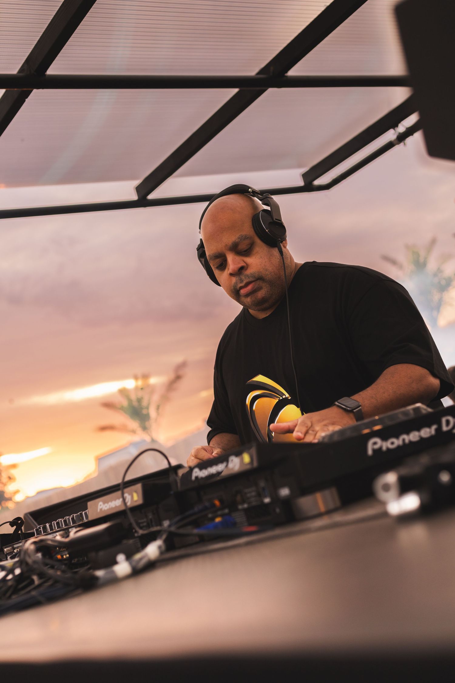 DJ performing at sunset with Pioneer equipment in close-up view.