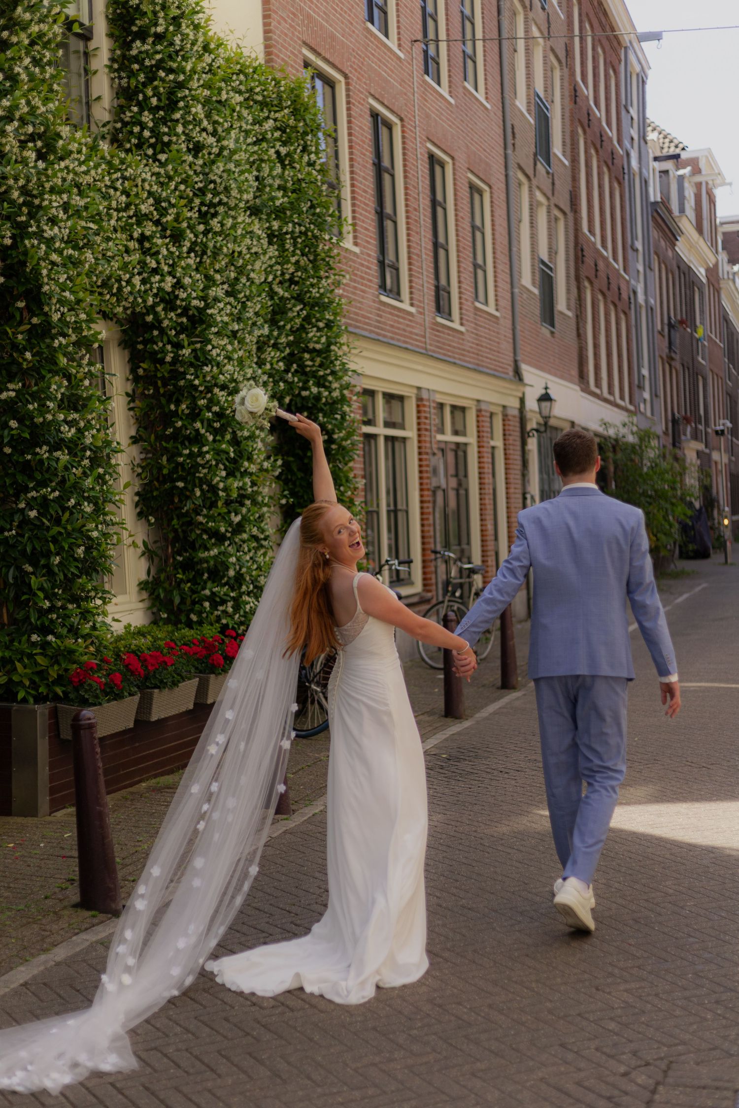 Wedding couple walks down a picturesque cobblestone street lined with historic buildings.