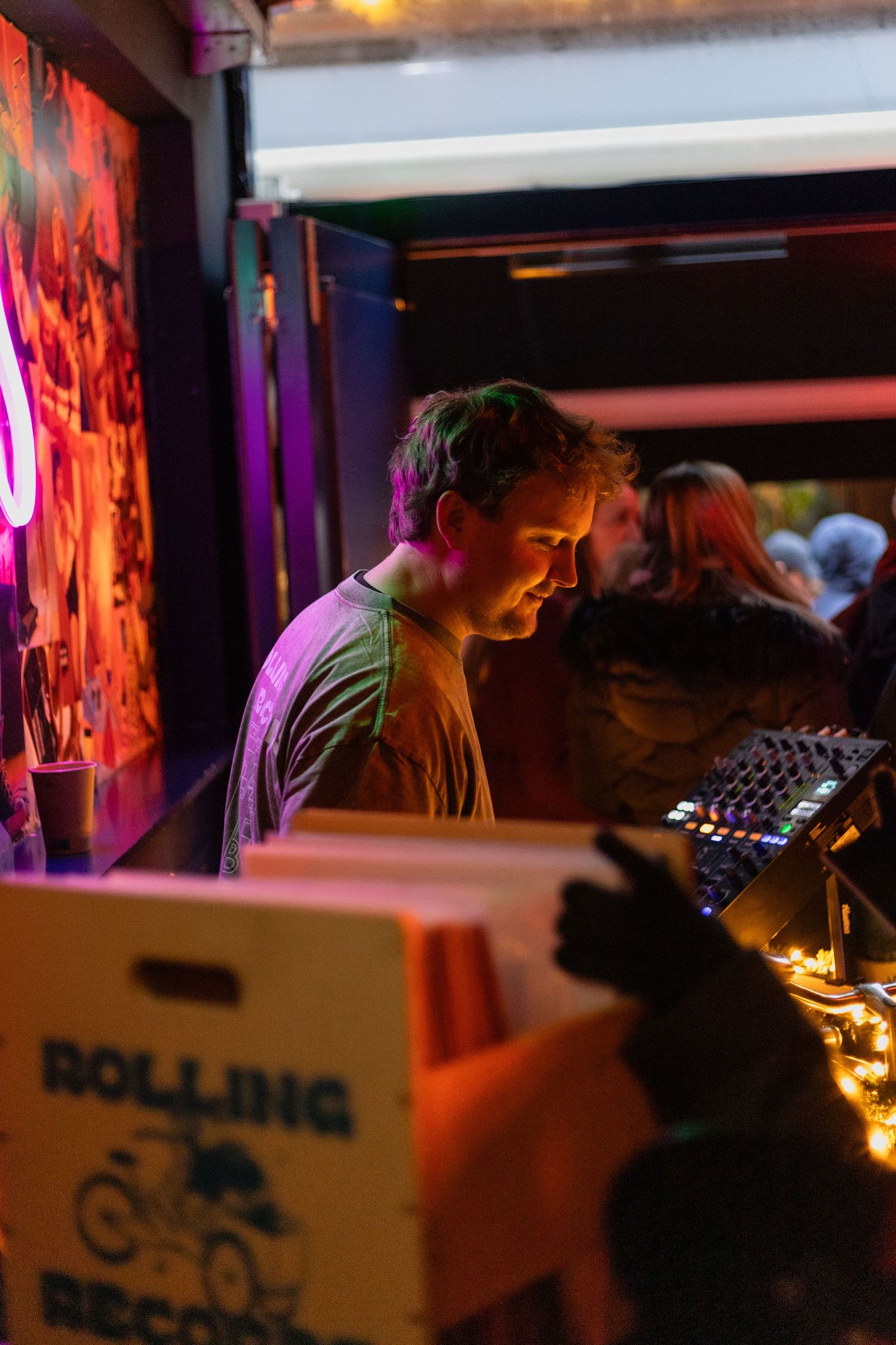 DJ performing in dimly lit bar with equipment and ambient lighting.