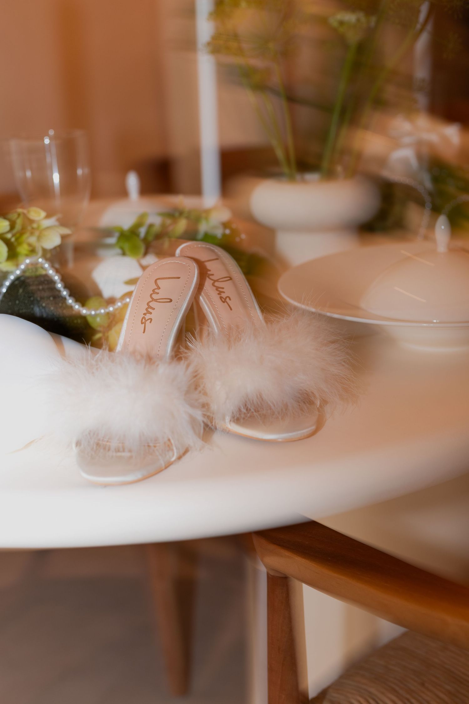 Elegant wedding table setting with delicate white feathers and soft candlelight creating a romantic atmosphere.
