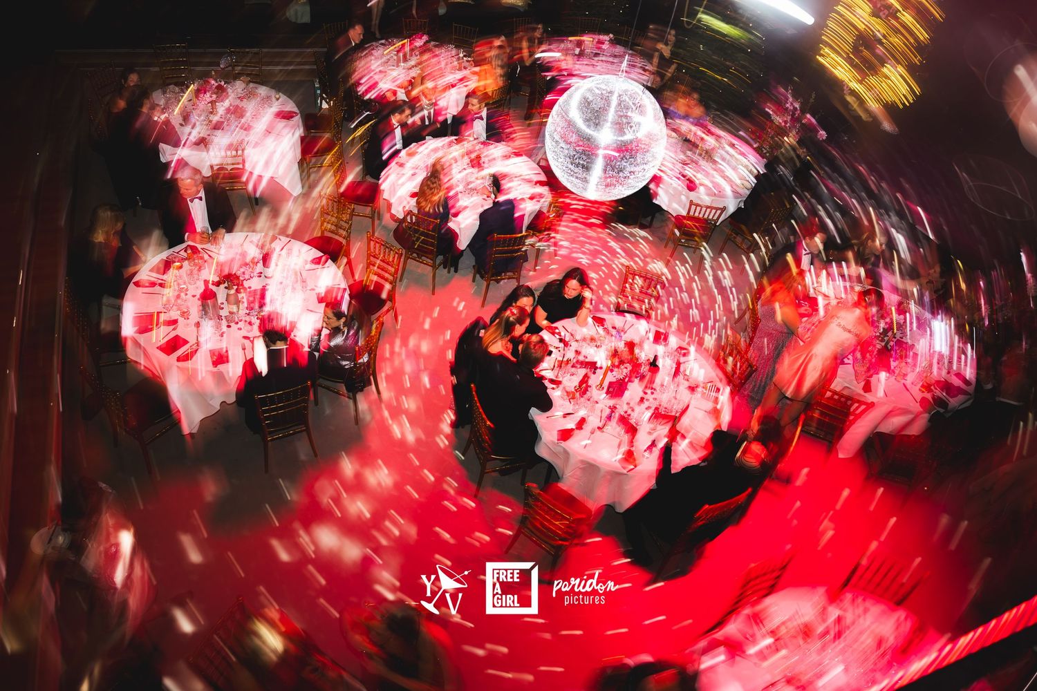 Abstract red light trails and motion blur create a swirling vortex pattern in a nighttime scene.