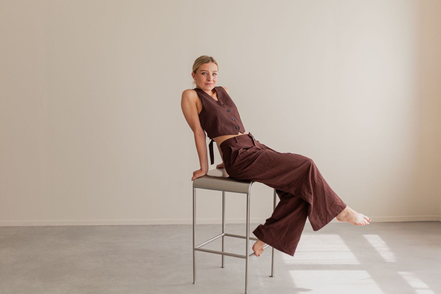 Figure in burgundy outfit demonstrates various poses on metal furniture.