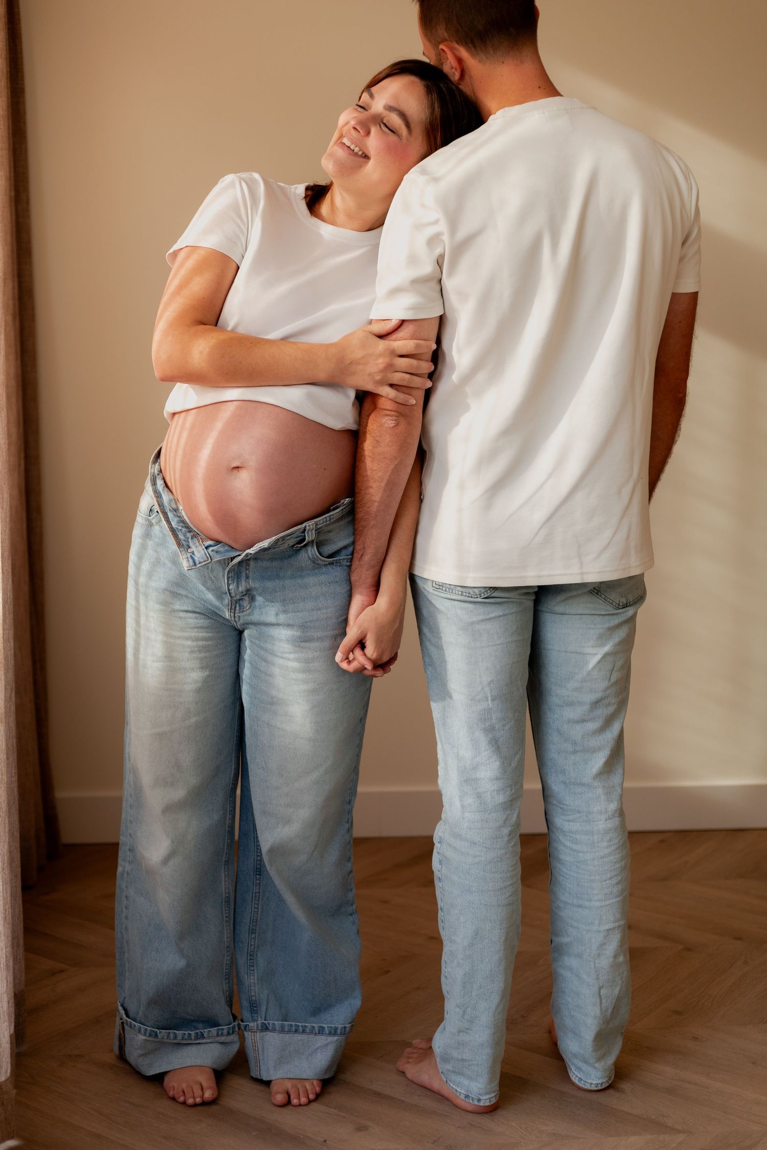 Four connected images showing a mother and child's legs in casual jeans and bare feet standing together against a wall.
