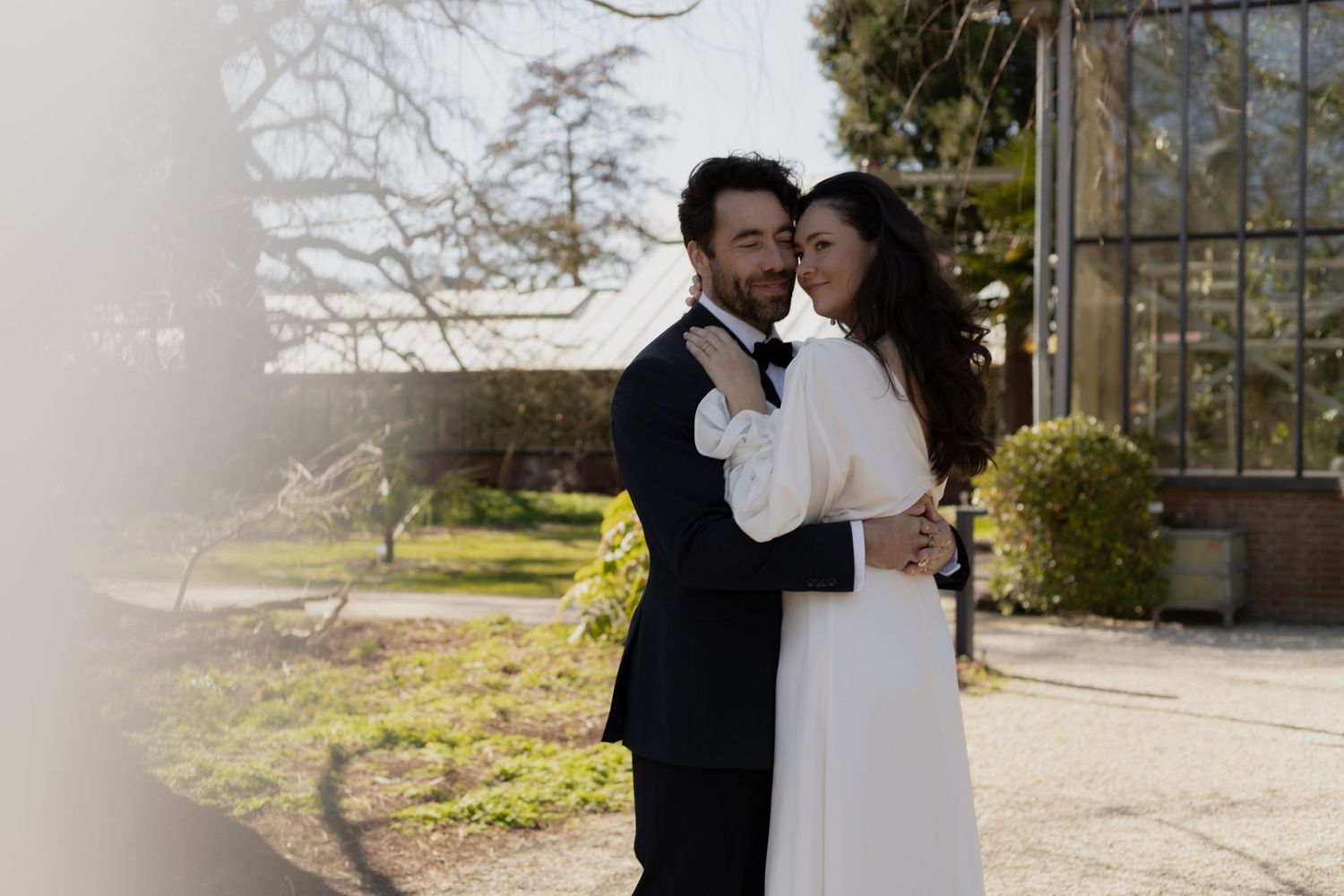 Newlyweds embracing outdoors for wedding photos on a sunny day.
