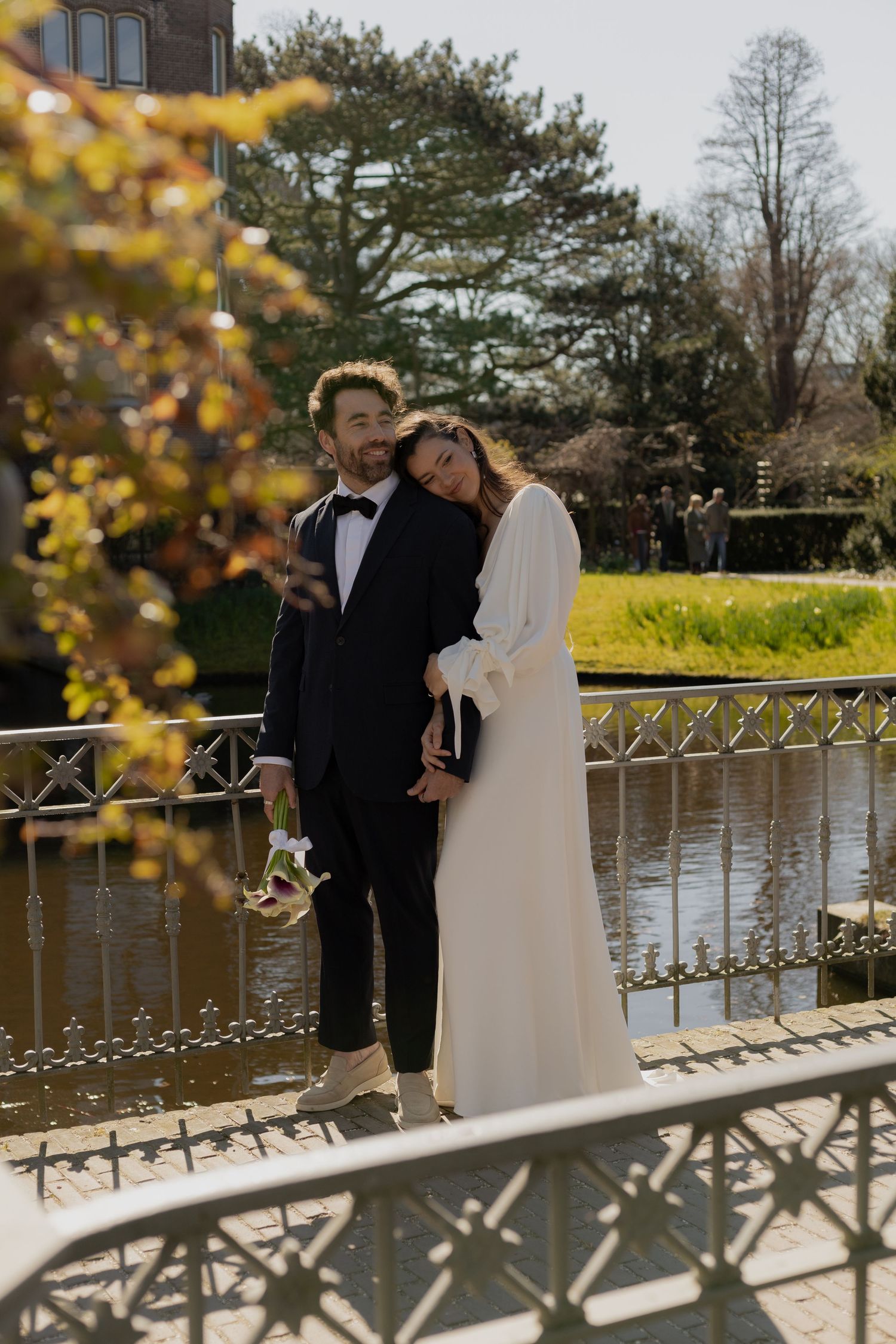 Newlyweds sharing an intimate moment by a lake during autumn with golden foliage.